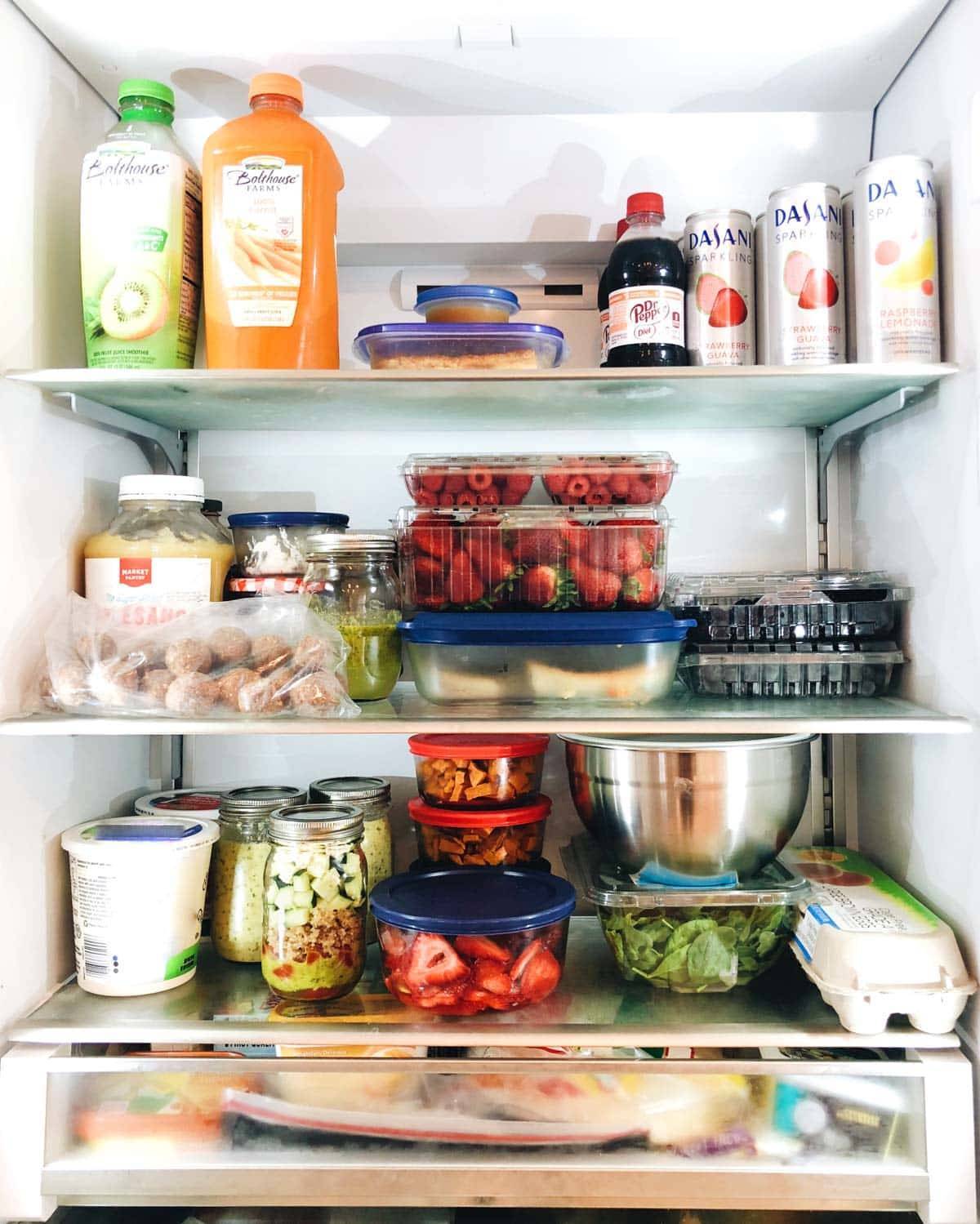 A refrigerator full of drinks, fresh fruits and canned food.