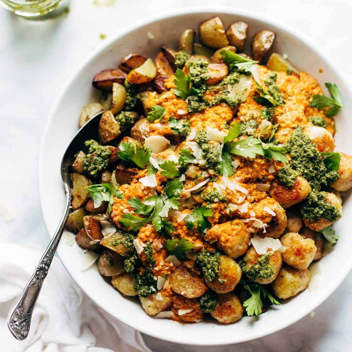 Mini Chicken Meatballs with roasted potatoes and romesco sauce in a bowl.