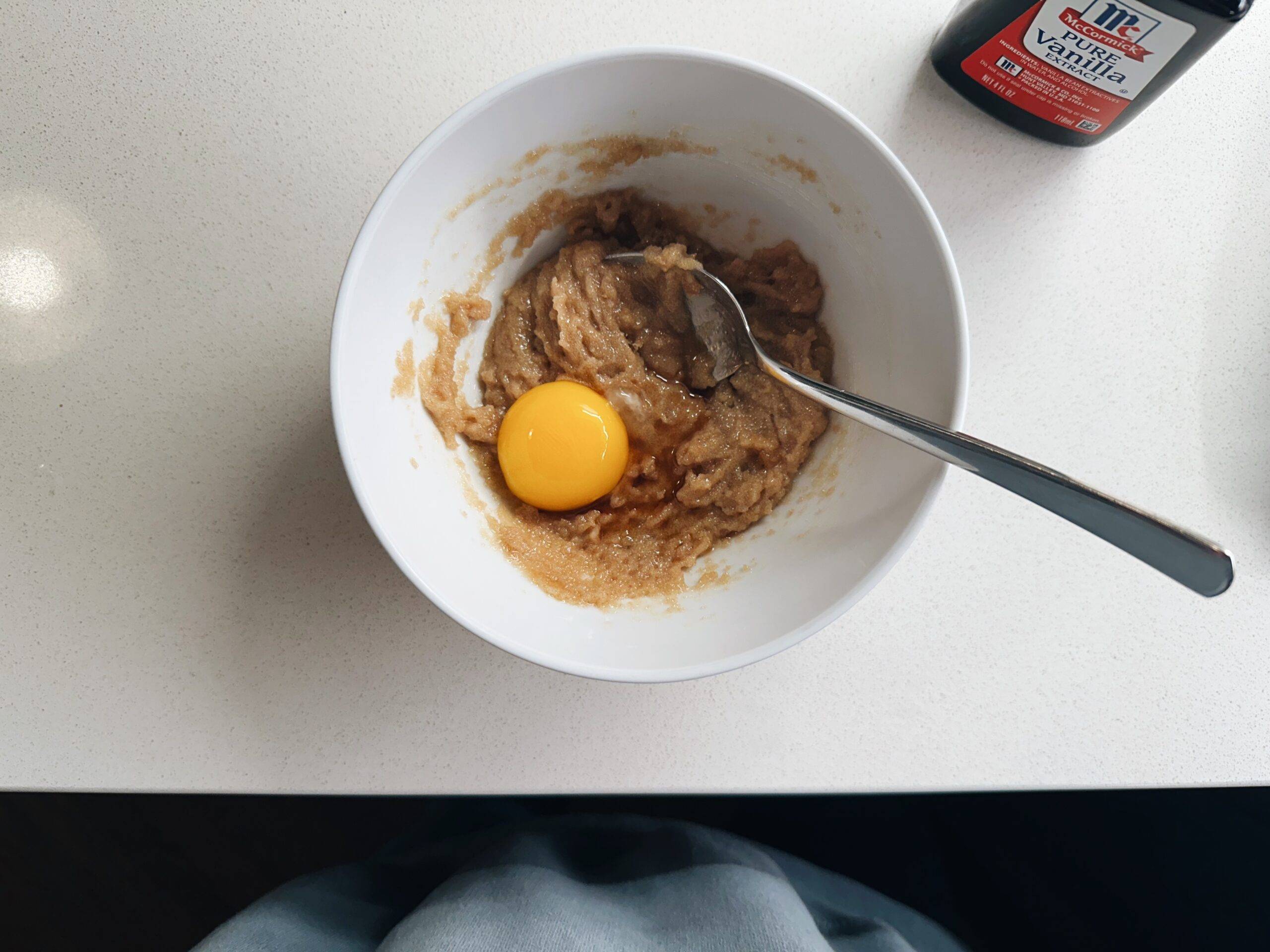 Butter and sugar in a bowl with an egg yolk.