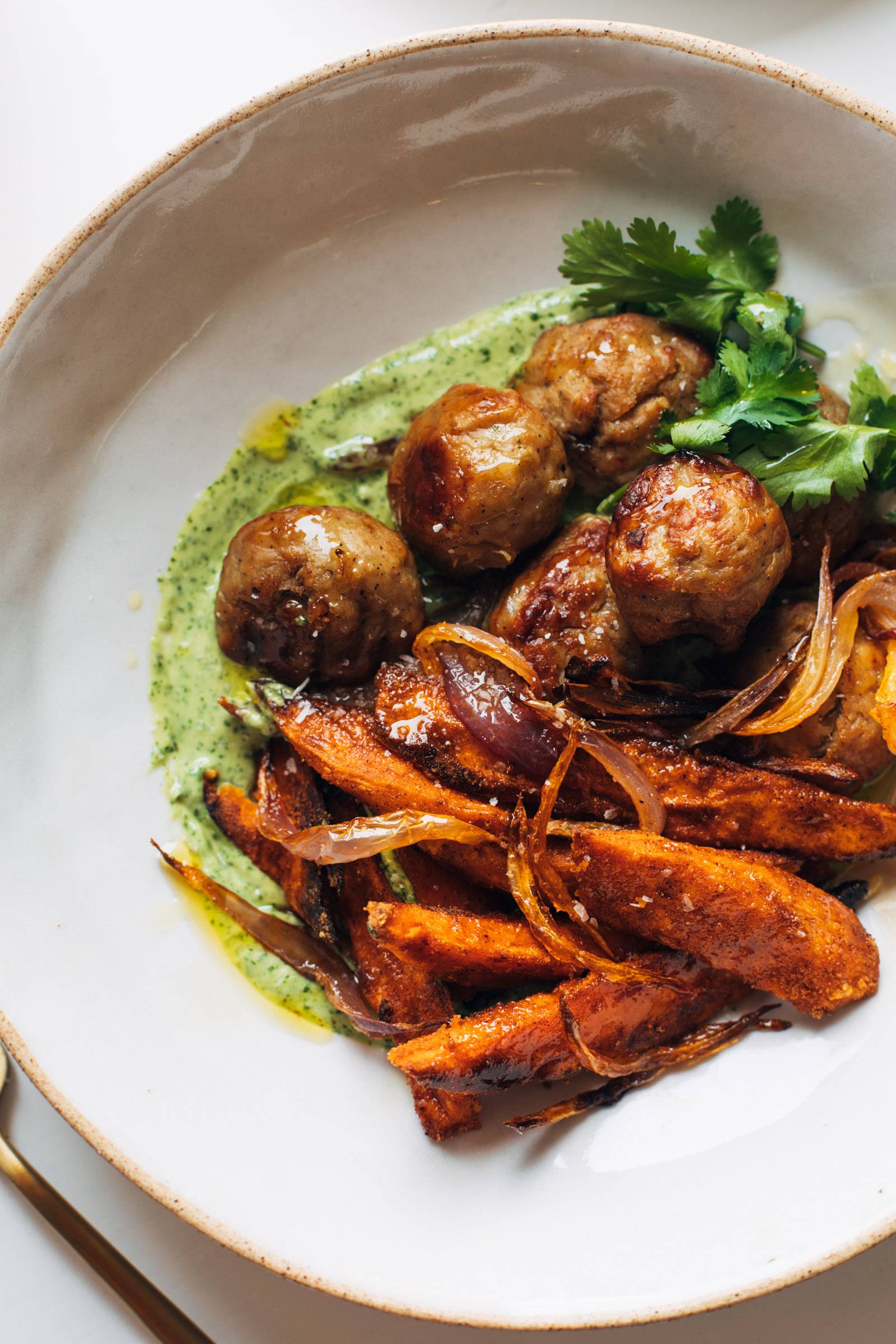 Chicken meatballs, sweet potato fries, and mojo sauce in a bowl.