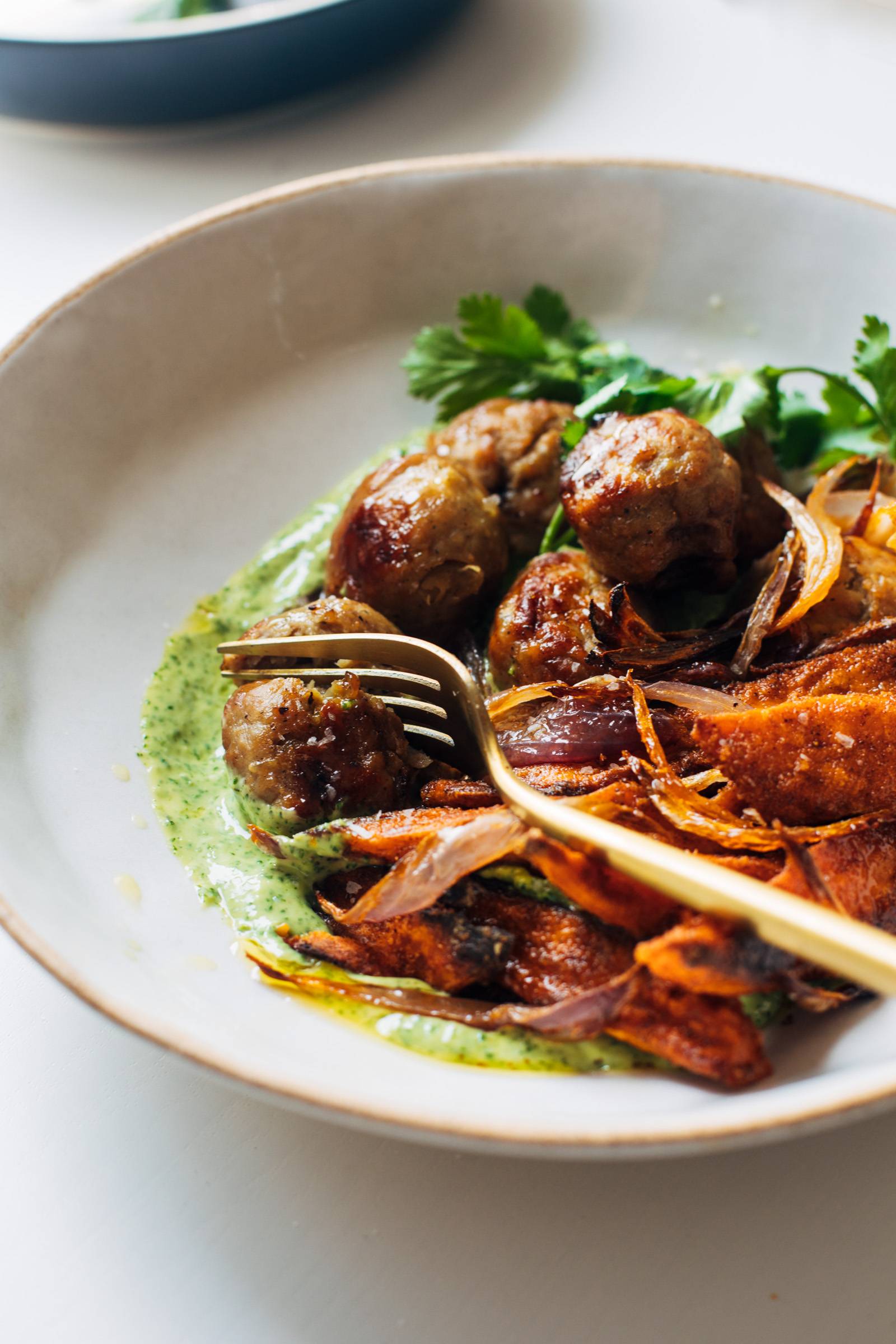 Fork digging into a meatball in mojo bowls