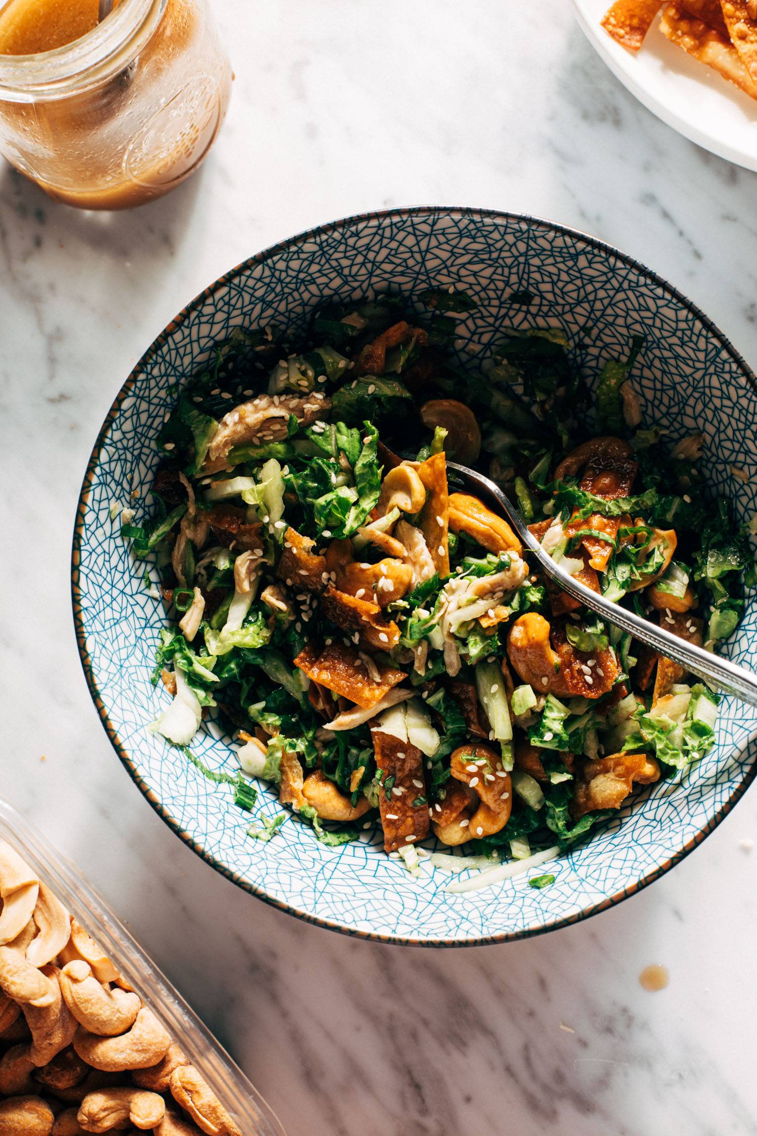 Napa cabbage salad in a bowl with a fork and cashews on the side