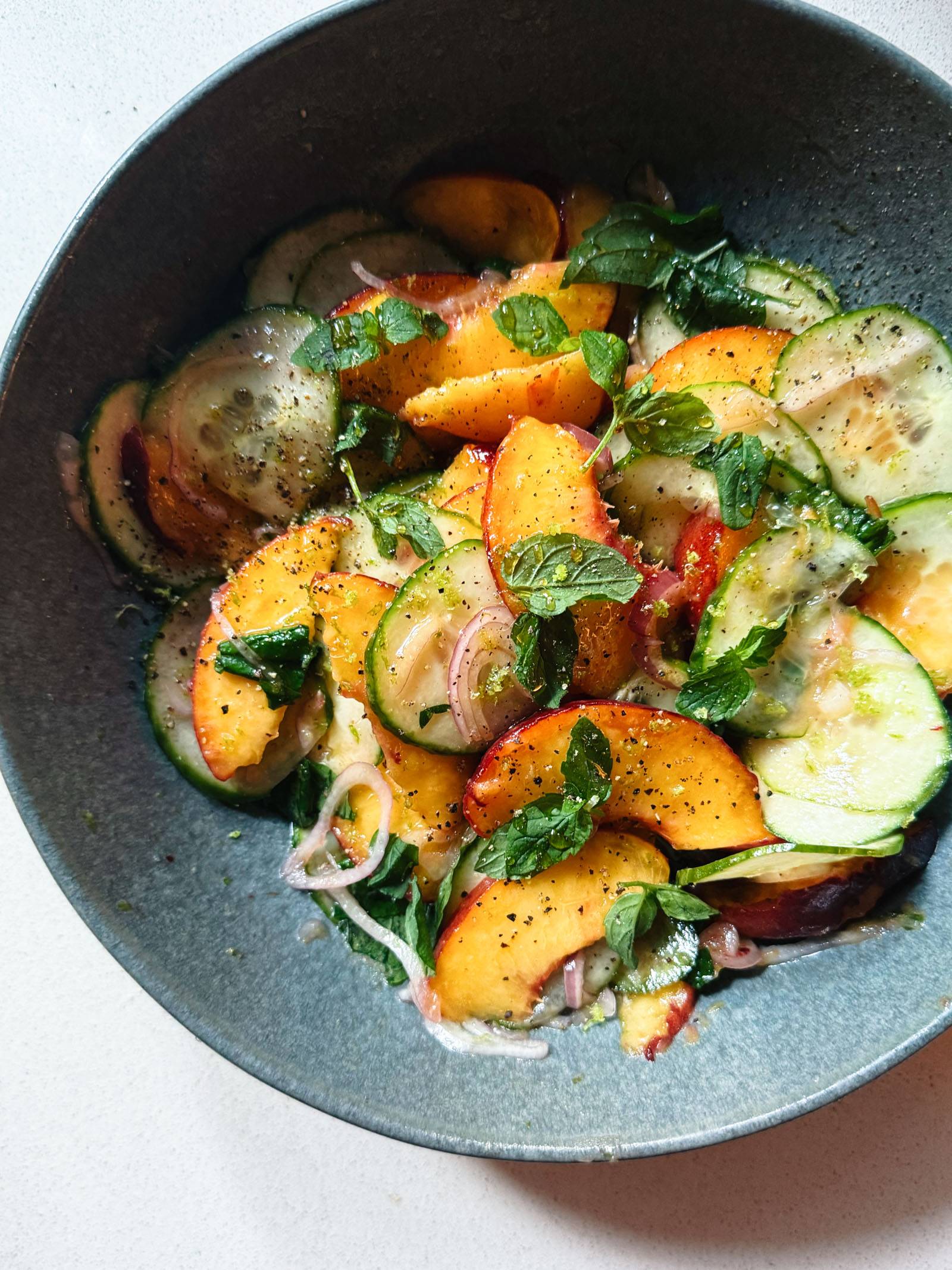 Peach salad in a bowl with mint leaves on top.