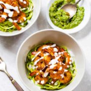 Two bowls havewith shrimp next to sauce.