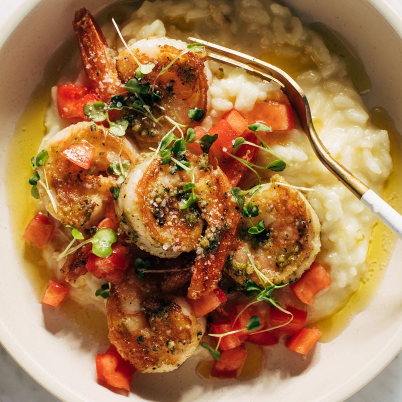 Pesto shrimp with risotto and a fork in a bowl