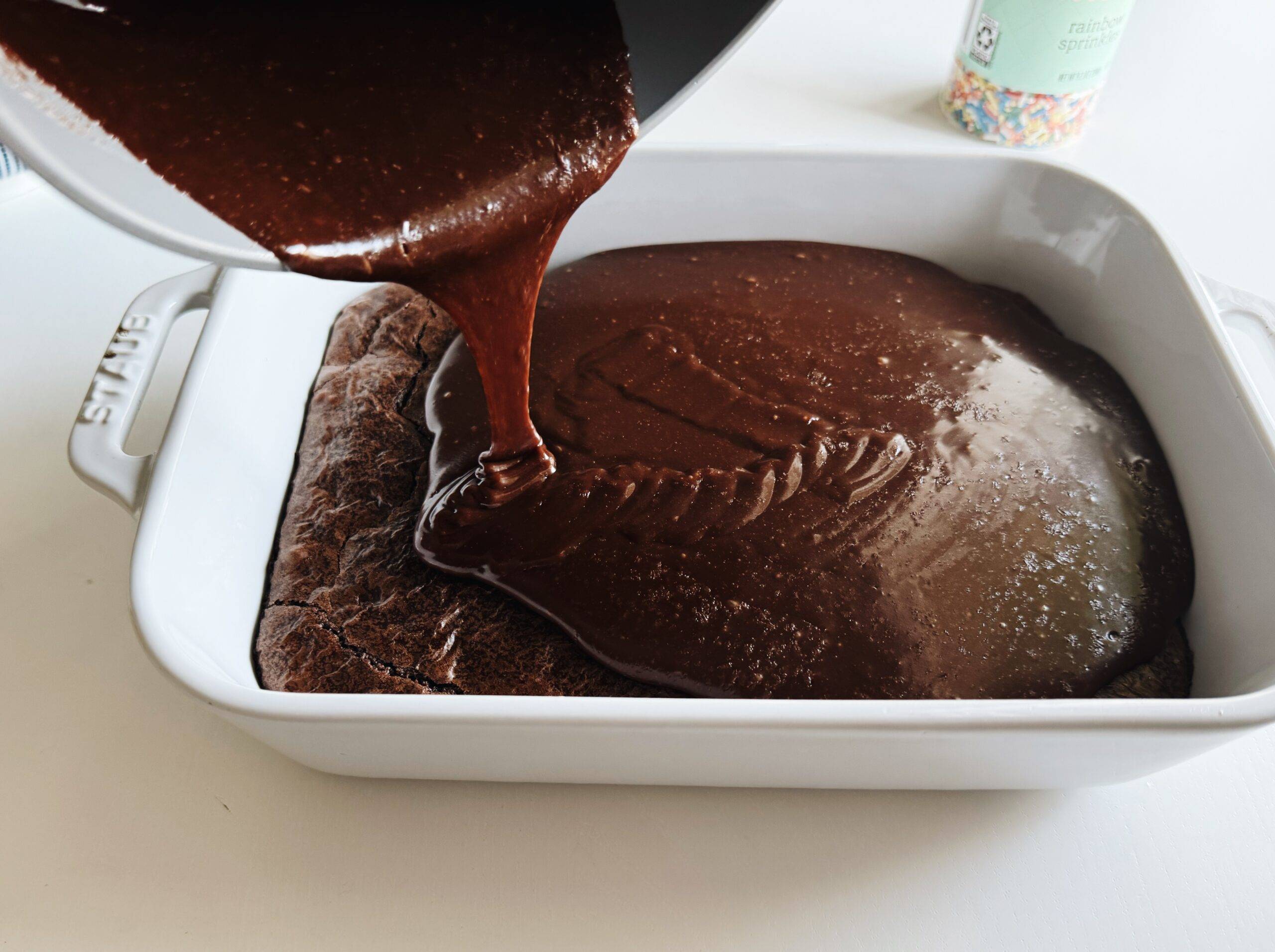 Pouring frosting on a pan of brownies.