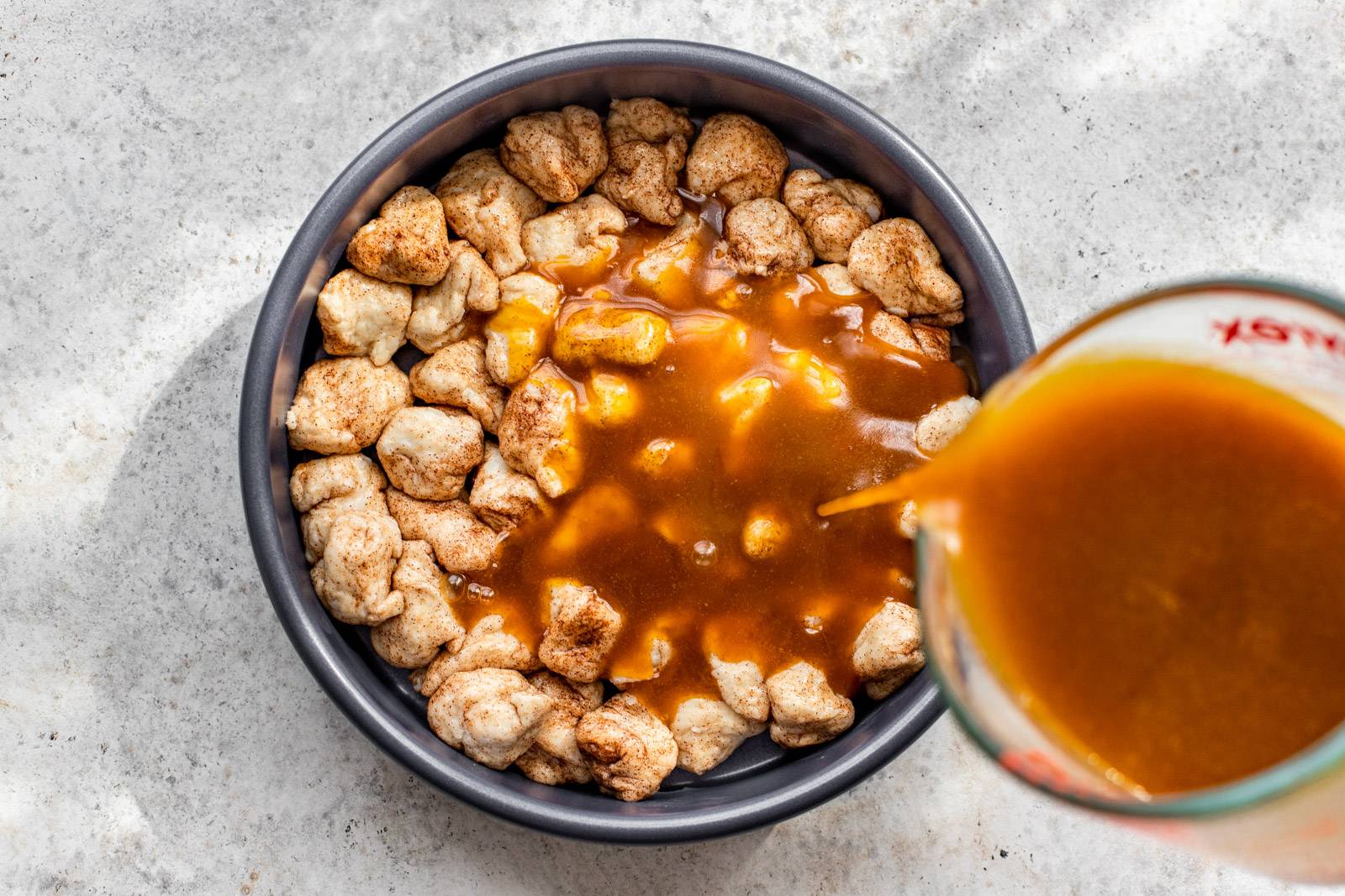 Baked dough being covered with pumpkin caramel drizzle.