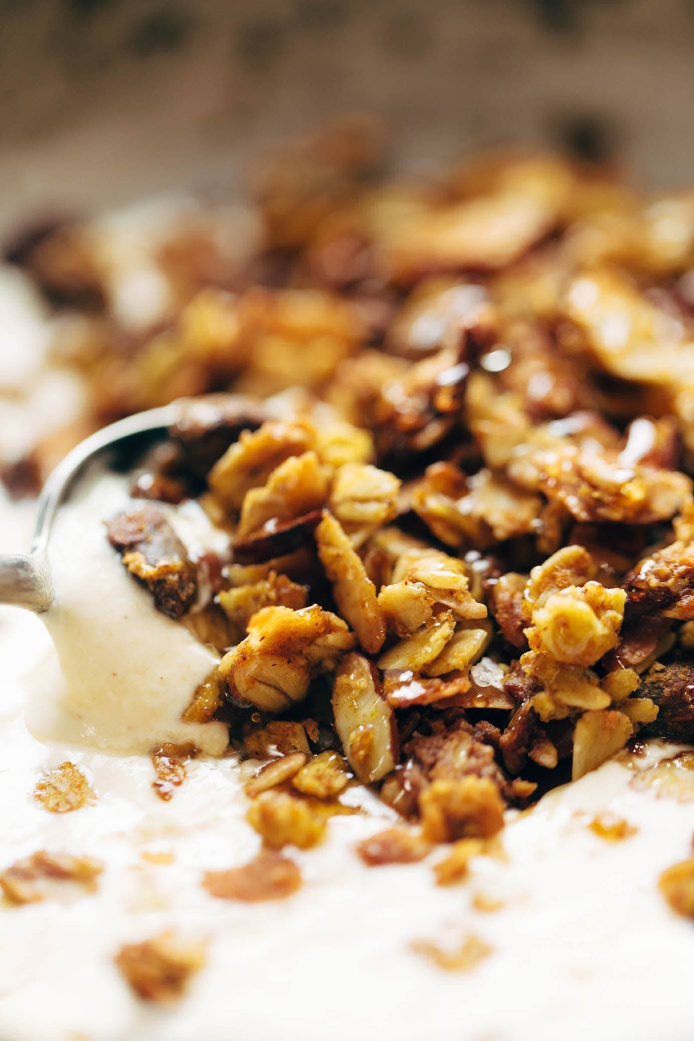 A close up photo of a spoon scooping pumpkin granola and yogurt.