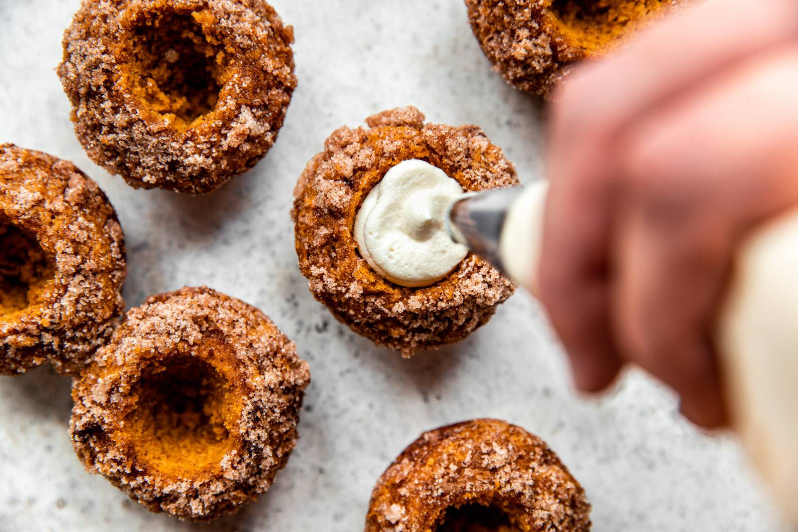 Piping in cream cheese to Pumpkin Muffins.