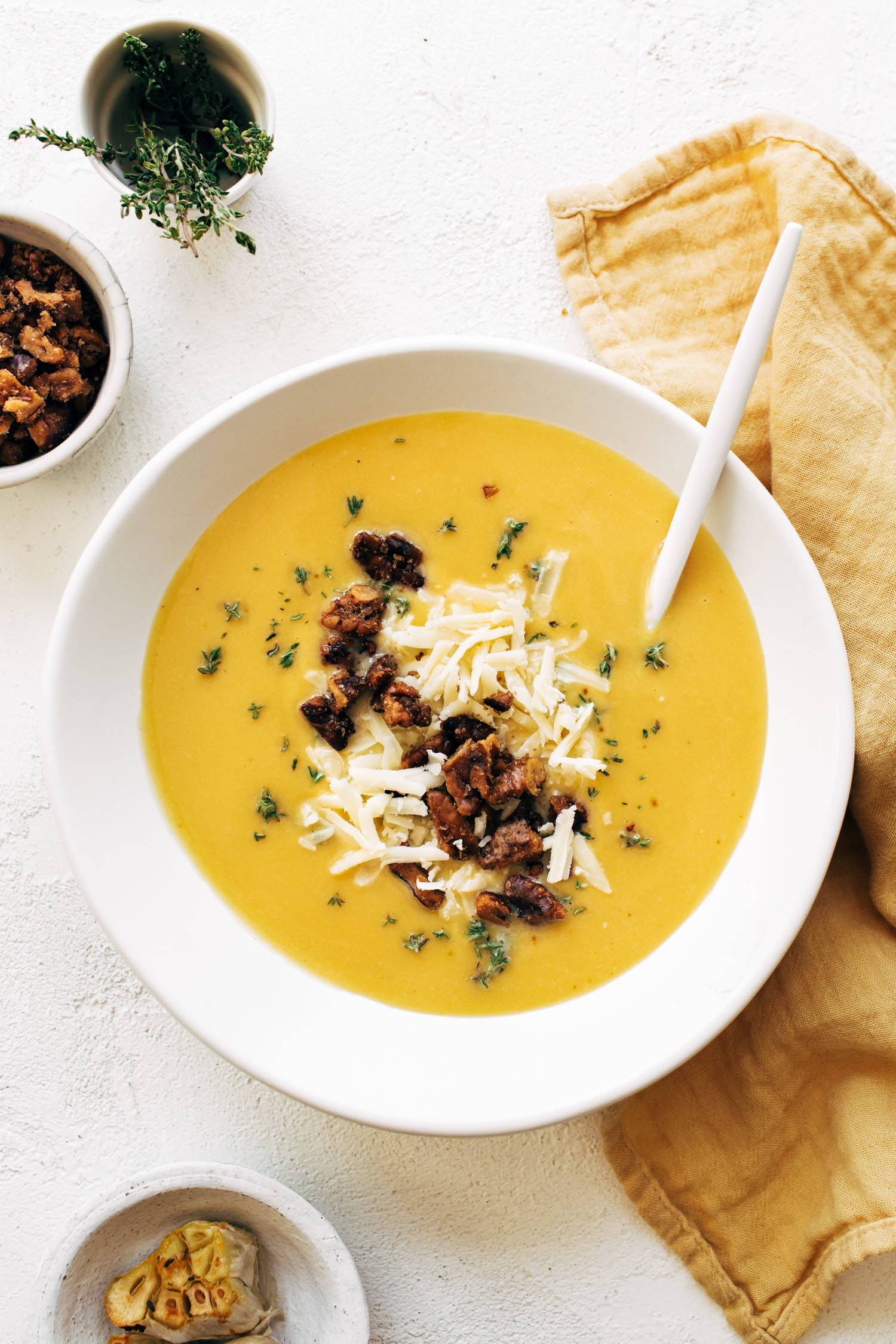 Pumpkin soup in a bowl with walnut crispies and cheese on top. There's a yellow napkin on the side.