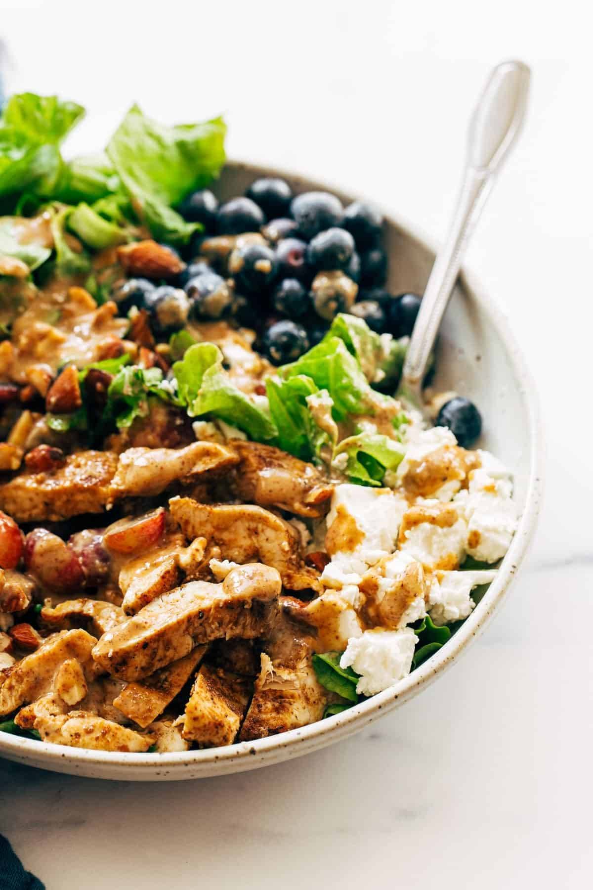 Rainbow chicken salad in a bowl with a fork