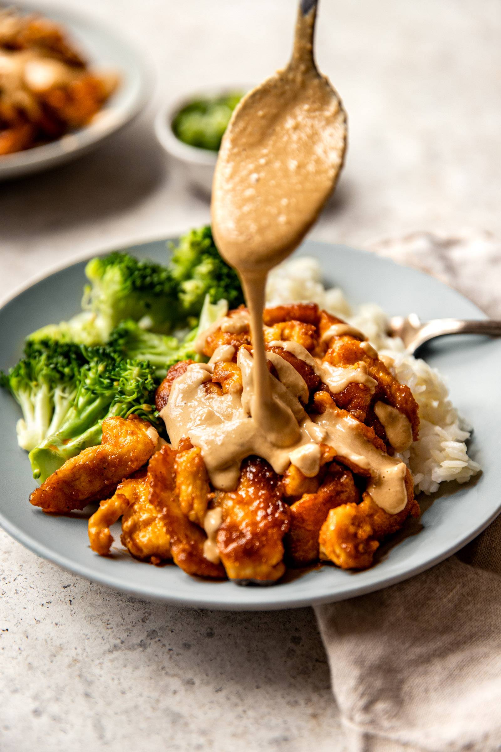 Cashew sauce getting drizzled on red curry chicken stir fry