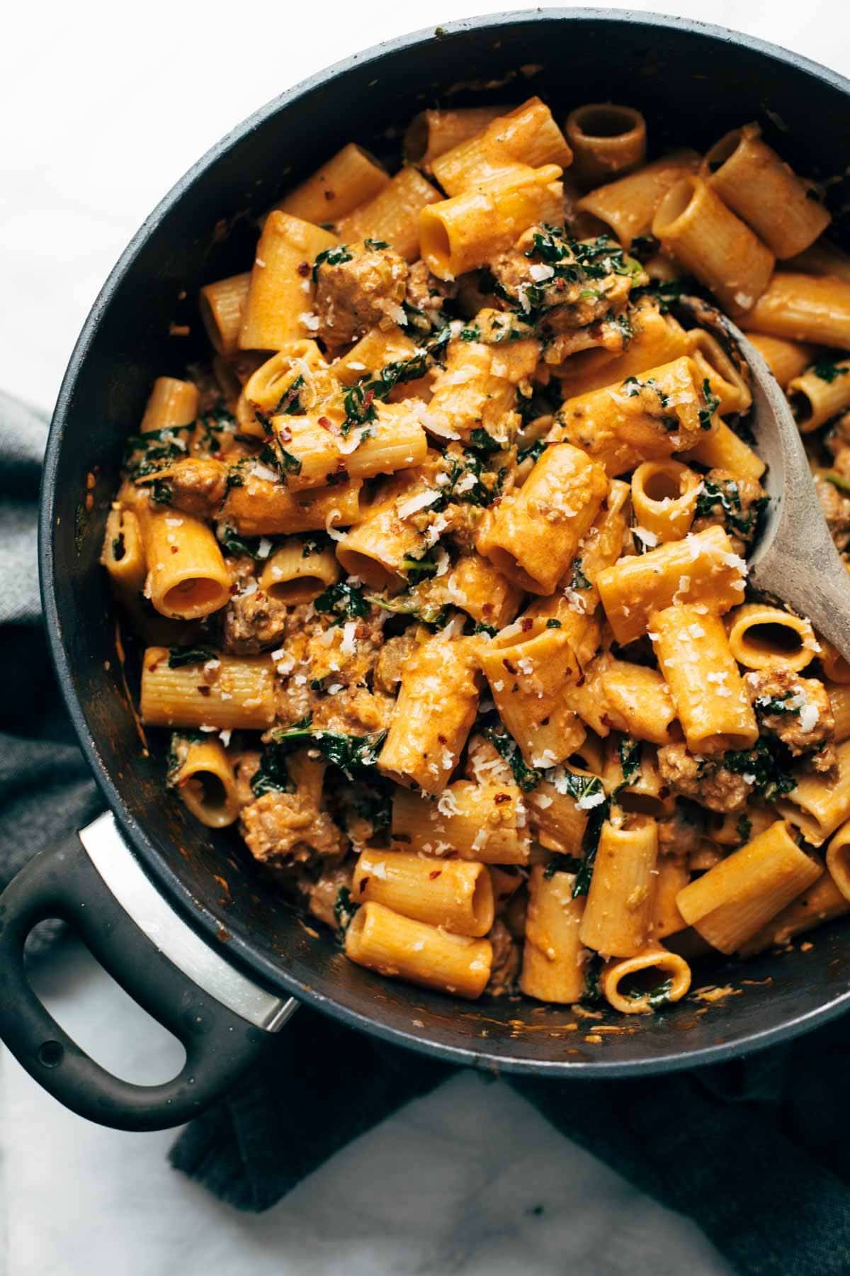 Rigatoni in a large pot with a wooden spoon.