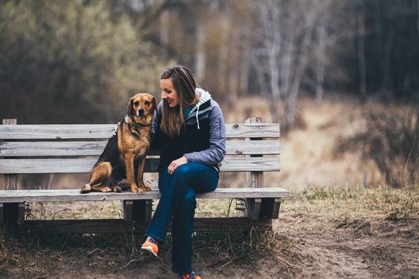 Woman sitting on a bench with a dog.