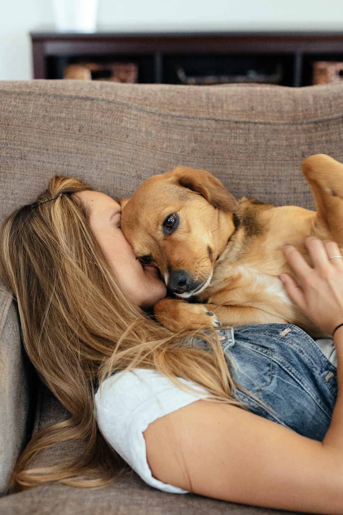 Woman and dog cuddling on a couch.