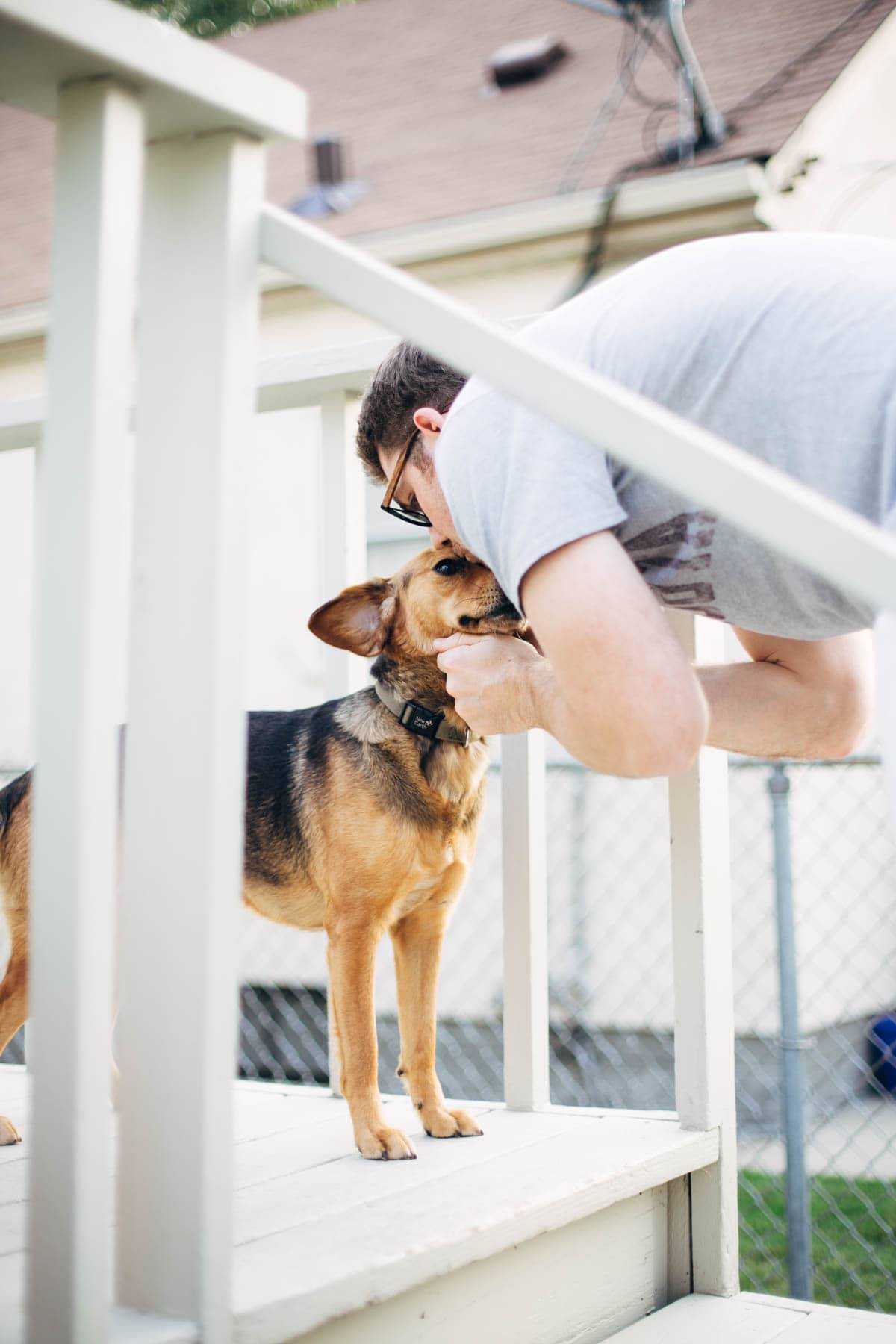 Man kissing a dog's head.