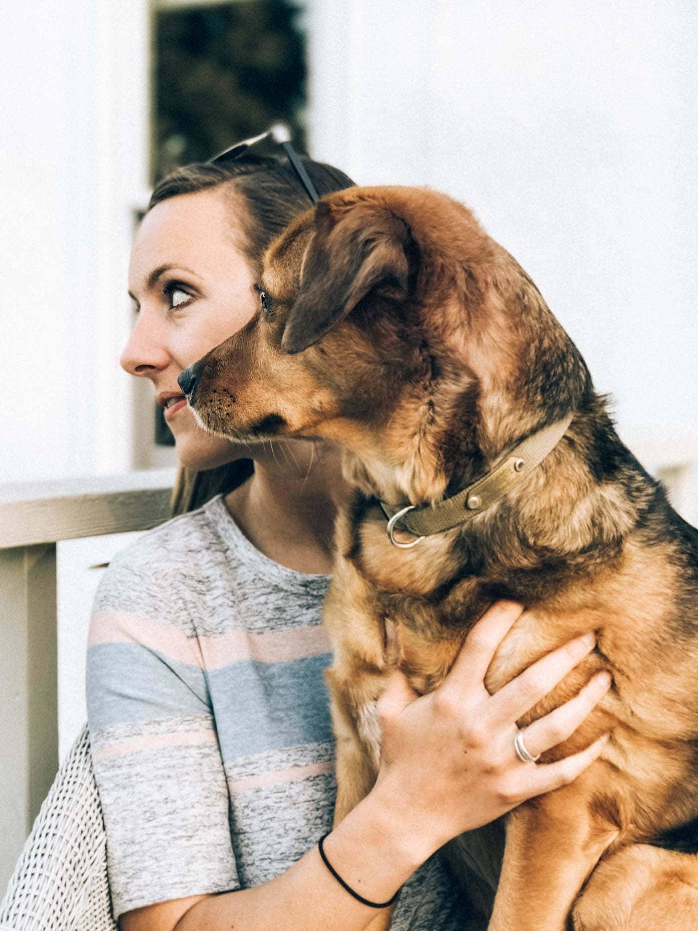 A woman holding a brown dog in her lap while she looks to the side.