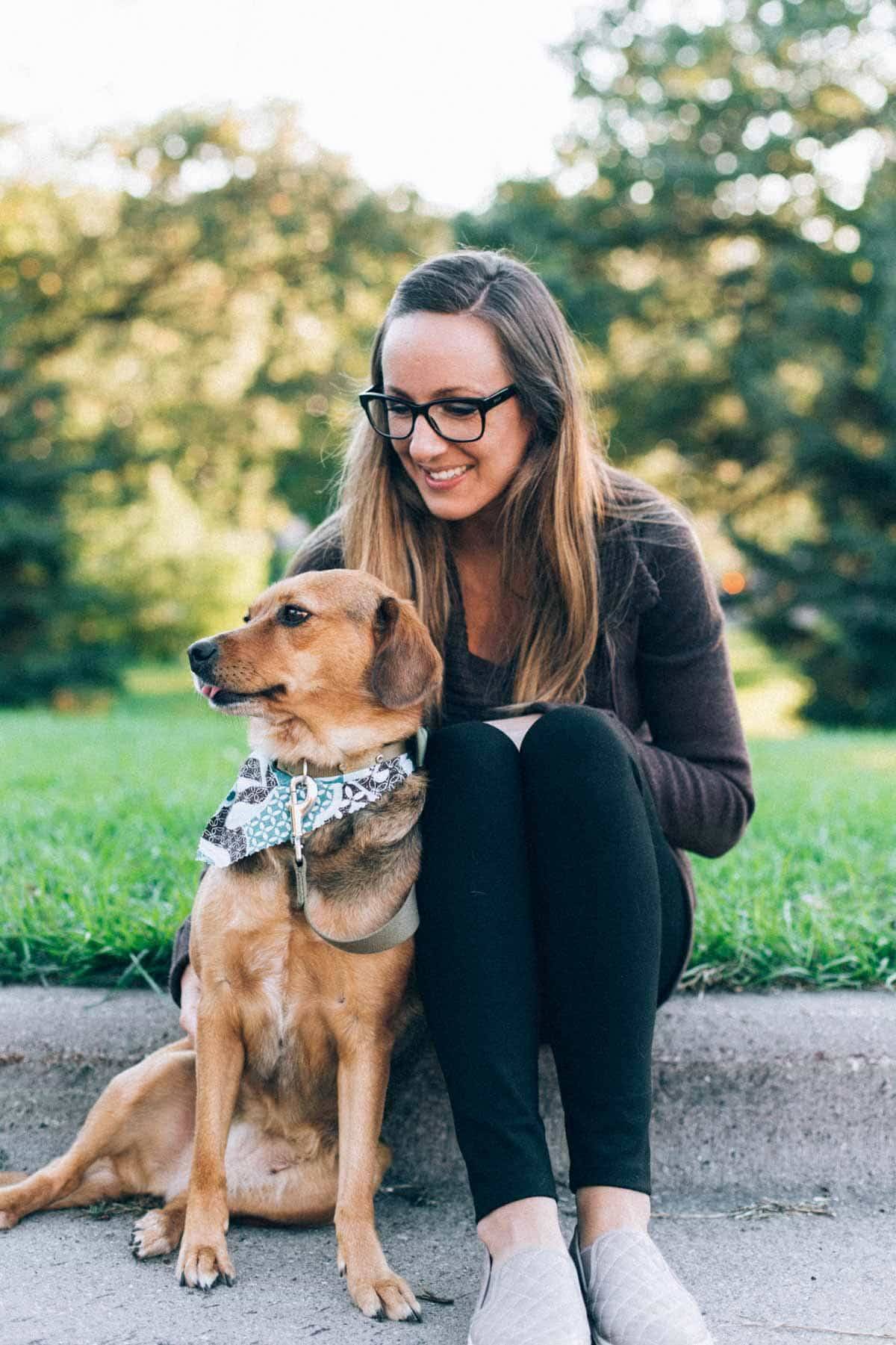 woman and dog sitting on a curb