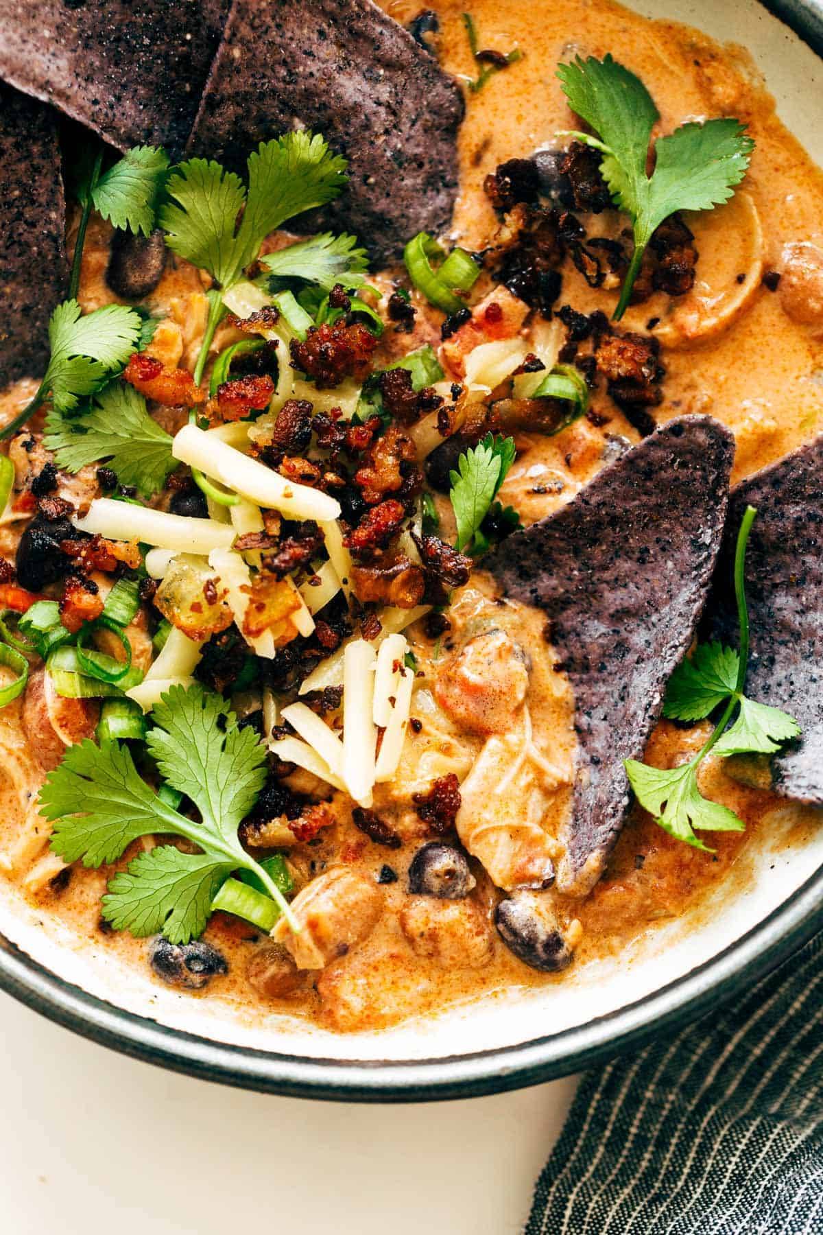 Chips in a bowls of chili and garnishments.