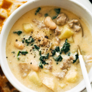 Sausage, kale, and bean soup in a bowl with a spoon.