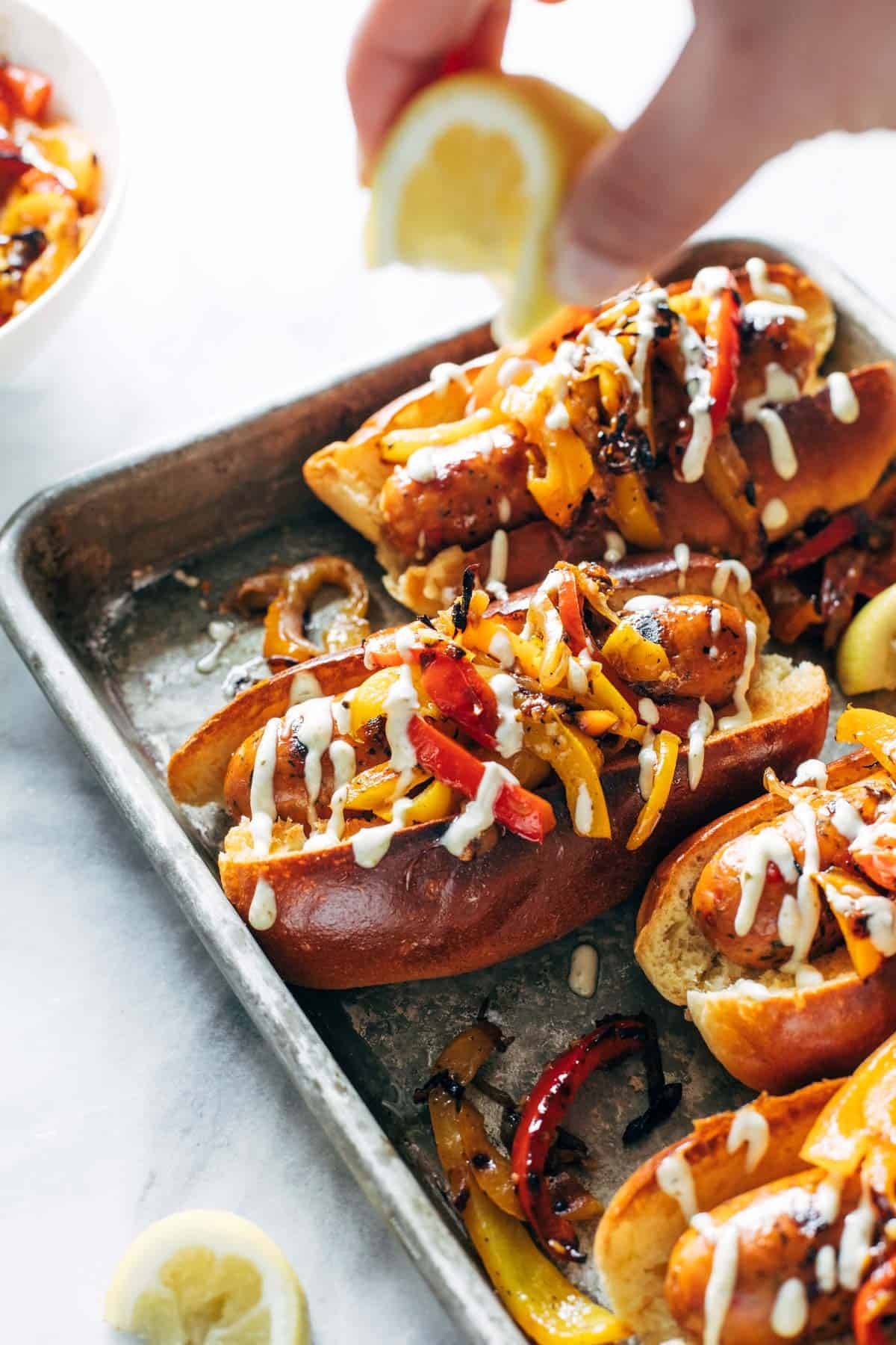 Grilled sausage and peppers on a sheet pan with a squeeze of lemon.