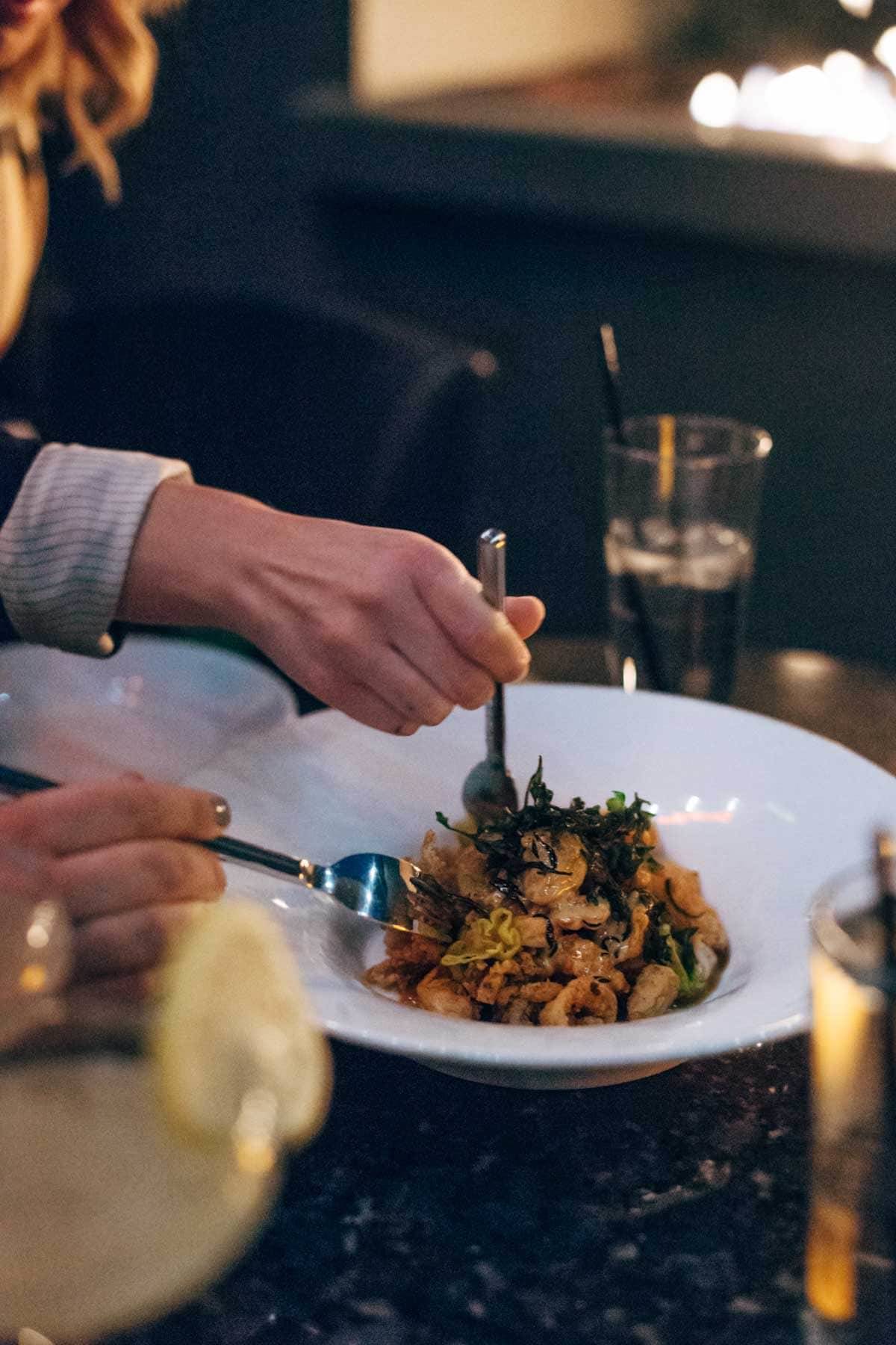 people with forks eating out of a bowl