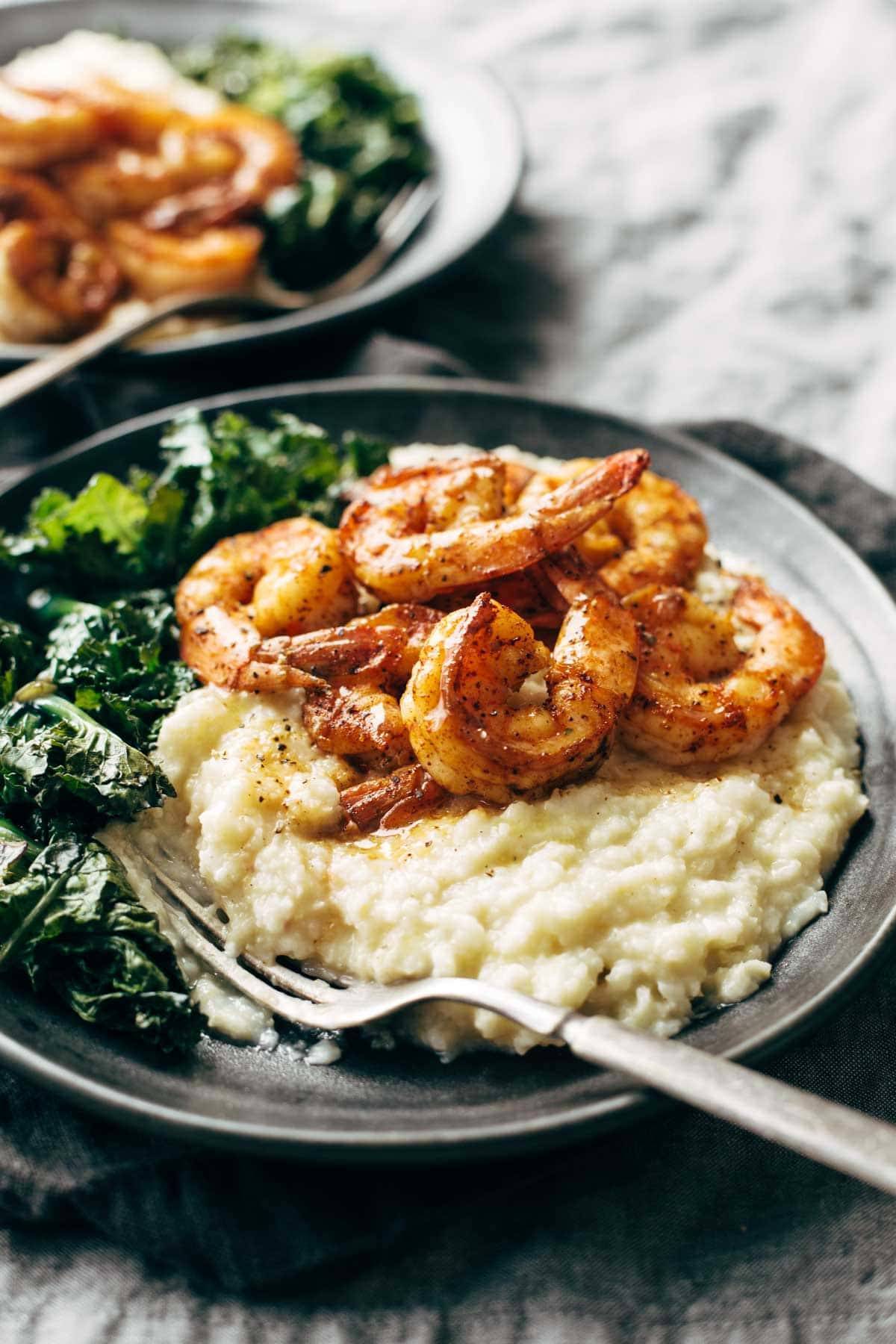 Spicy shrimp with cauliflower mash and kale on a plate with a fork.