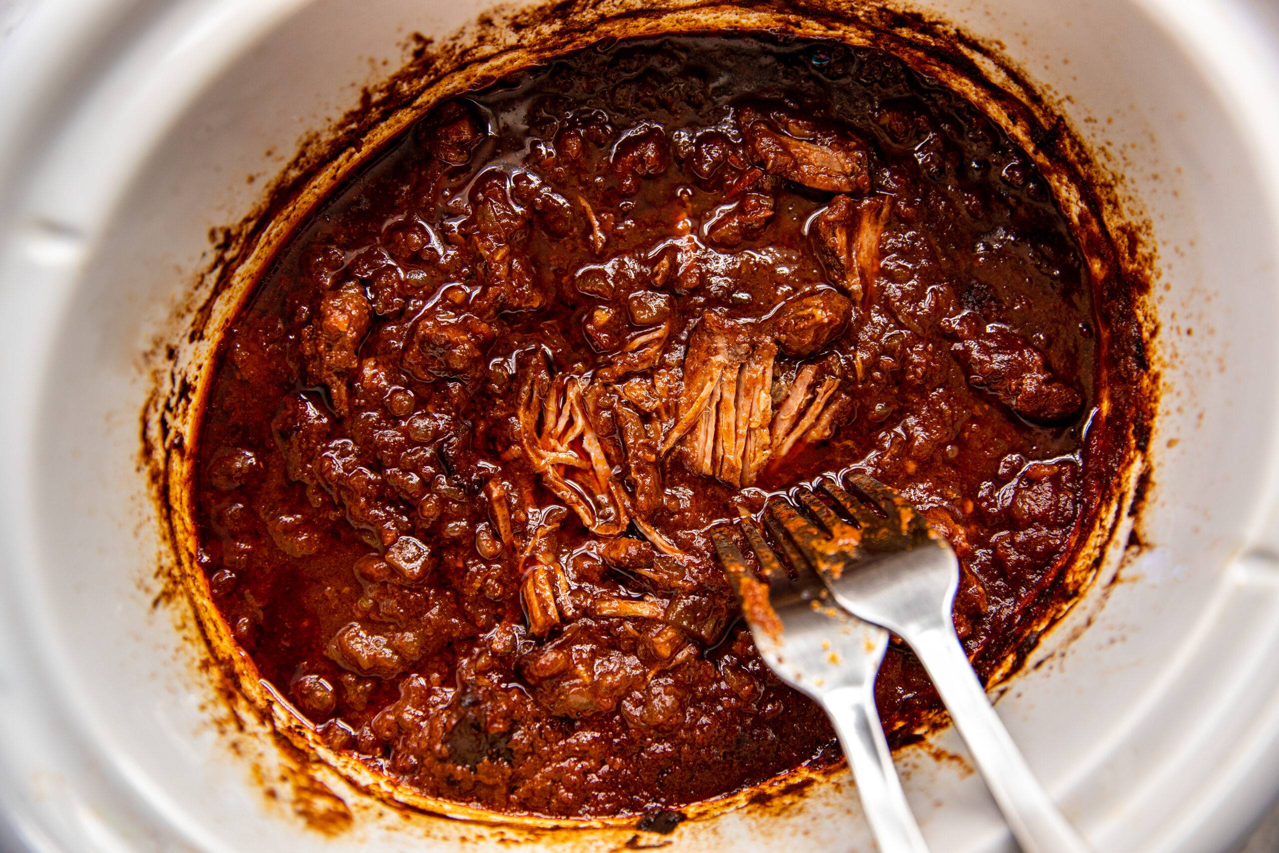 Shredding beef in a slow cooker with two forks.