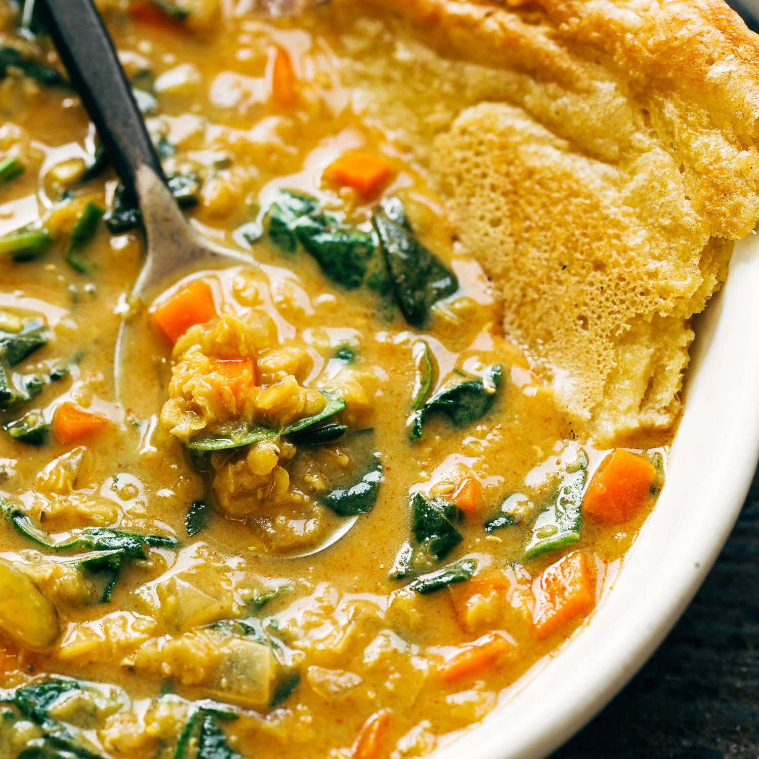 Red lentil stew in a bowl with socca.