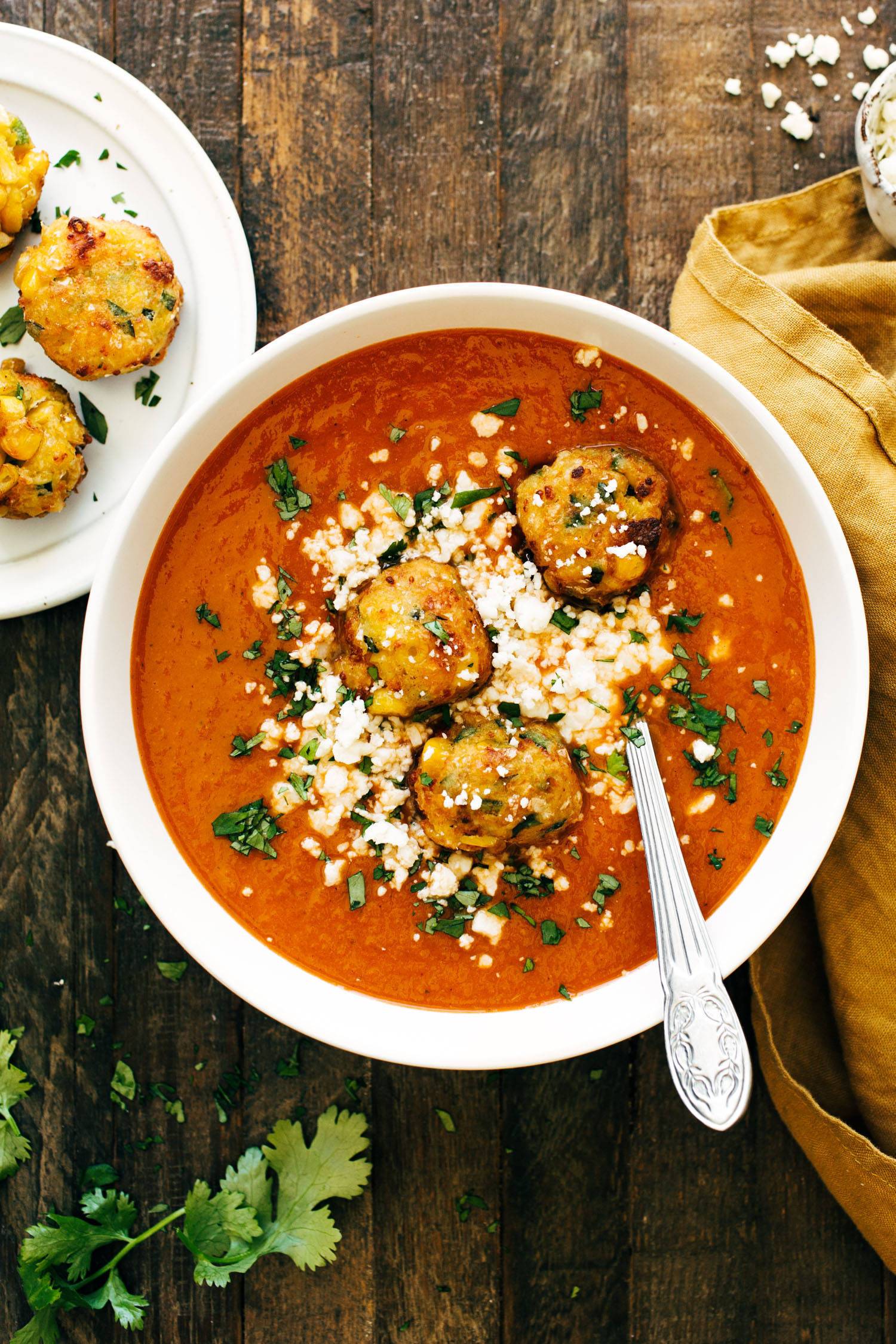 Sopa Tarasca in a bowl with a spoon and jalapeno corn fritters on top of the soup. 