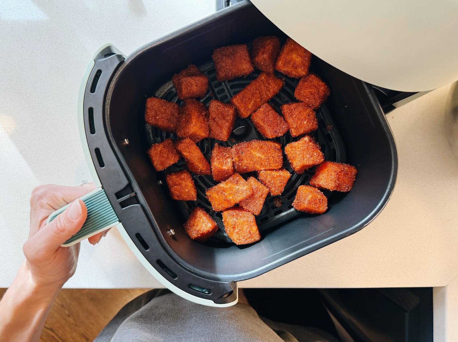 Coated salmon pieces in an air fryer.