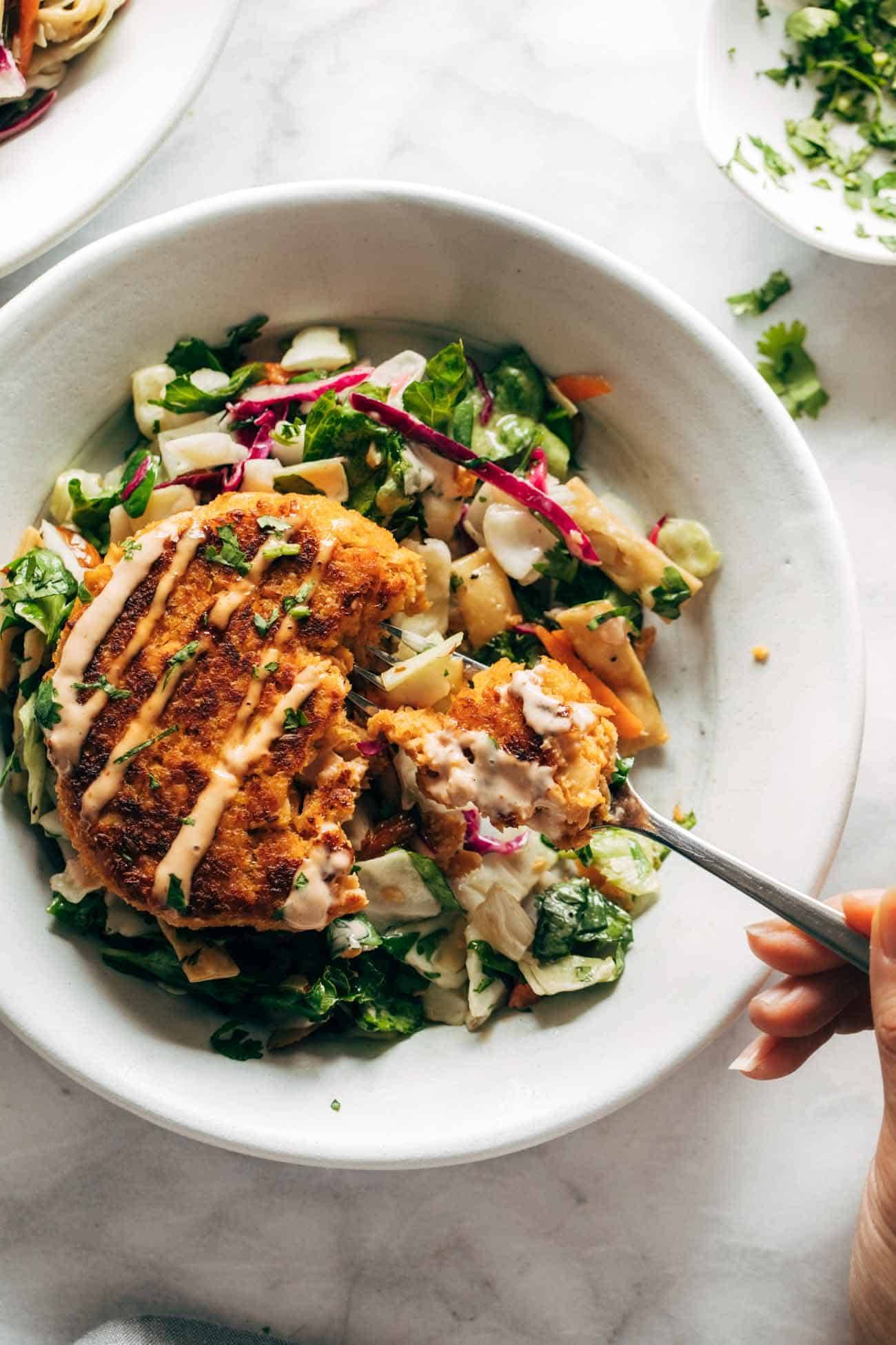 Salmon burgers on a plate with a salad and a fork