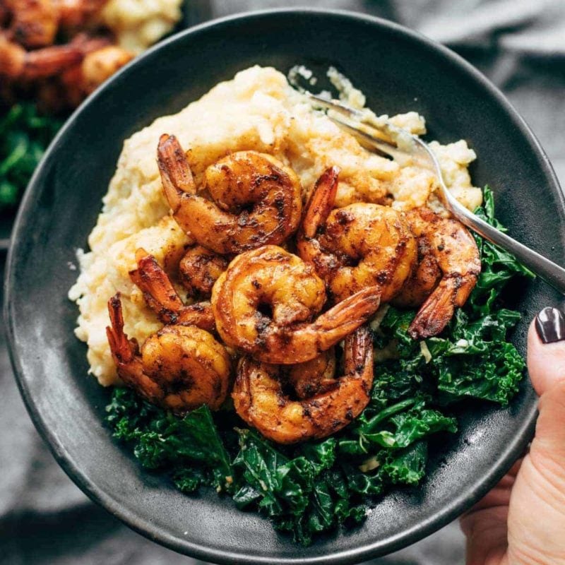 Spicy shrimp on a plate with mashed cauliflower and kale.