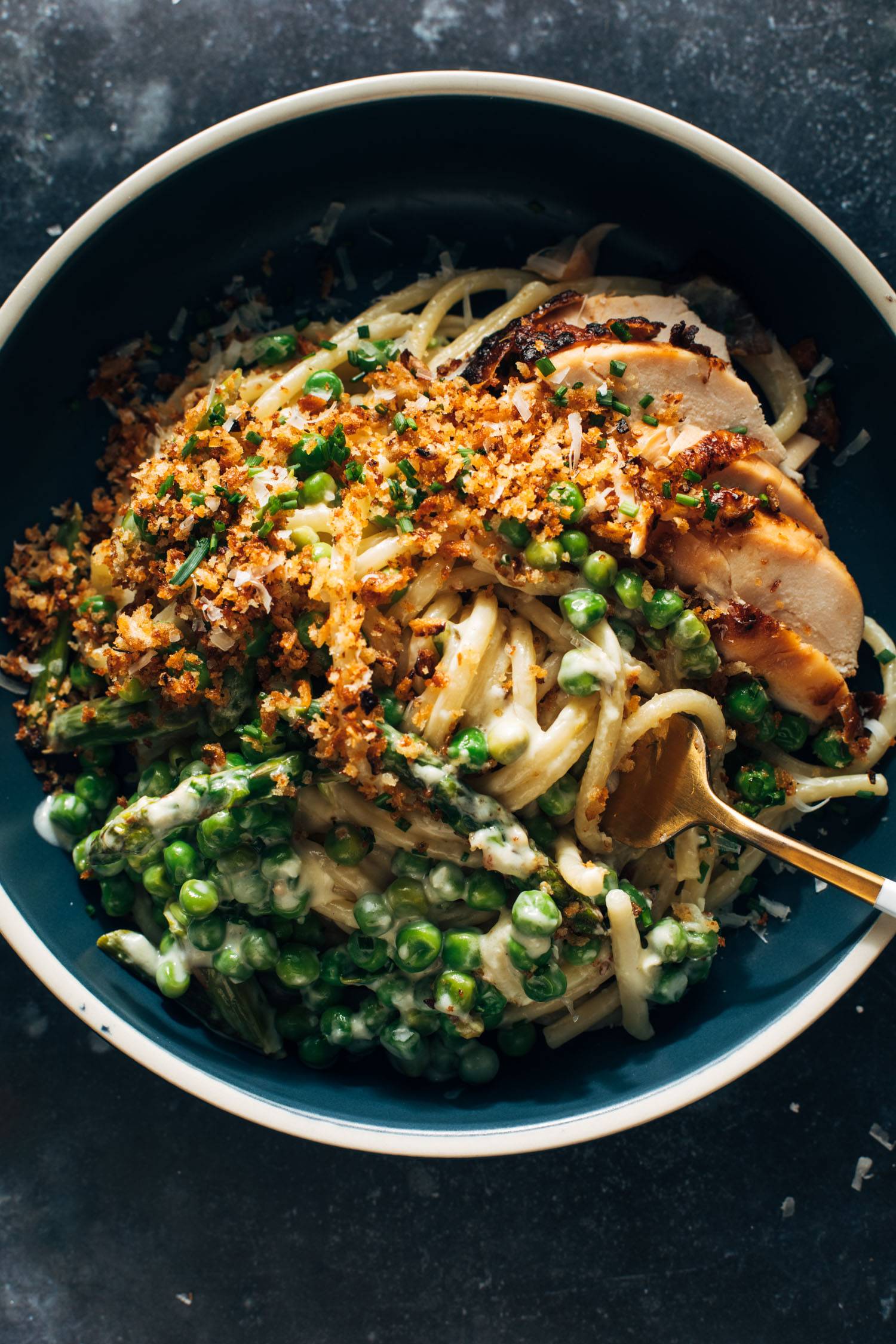 Bucatini pasta in a bowl with a fork and peas