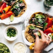 Steak Tacos on plates with hand squeezing a lime.