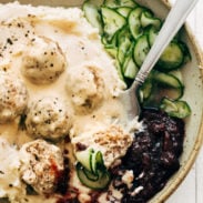 Swedish meatballs in a bowl with cucumbers and cranberries.