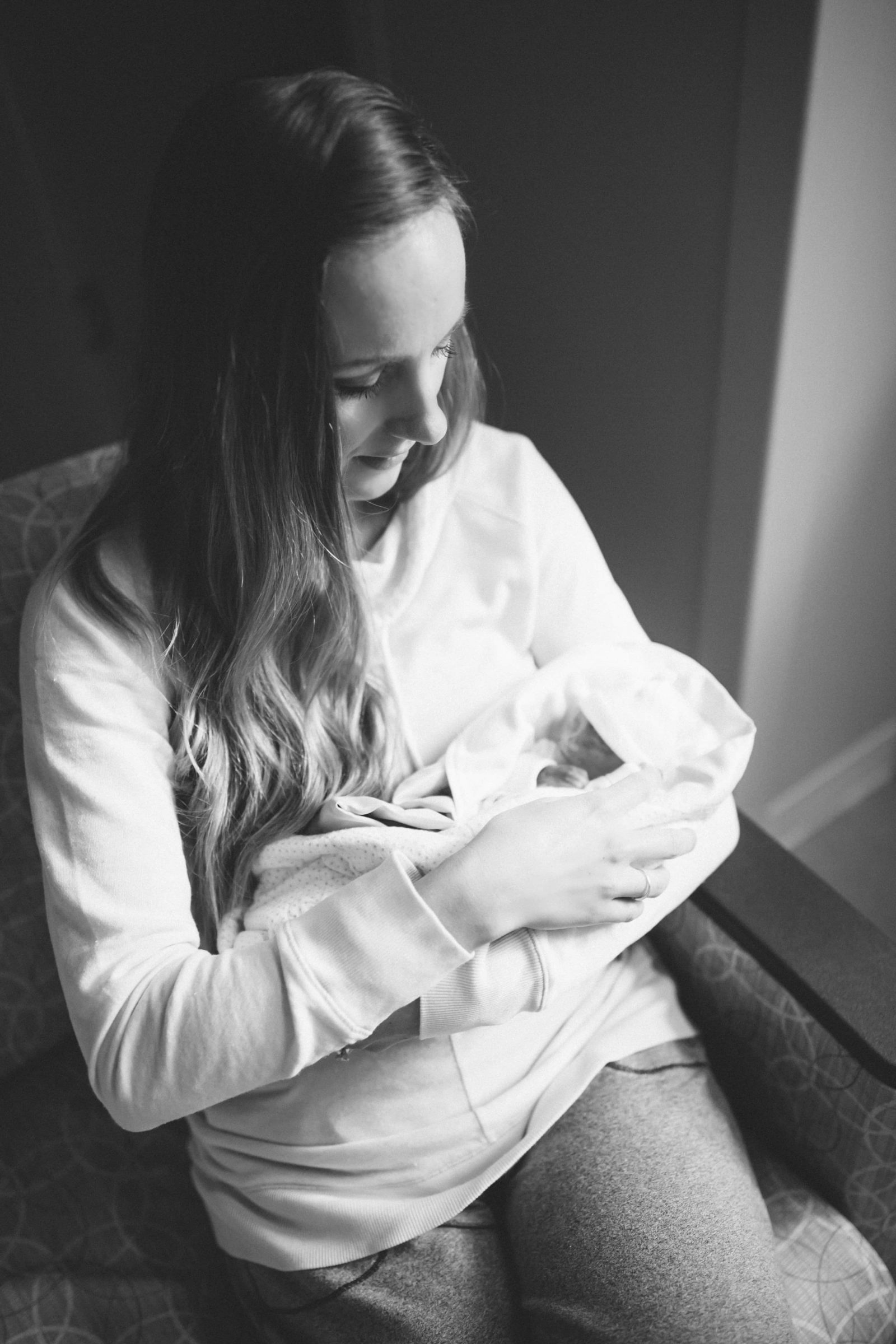 A woman sitting with a baby on her chest.