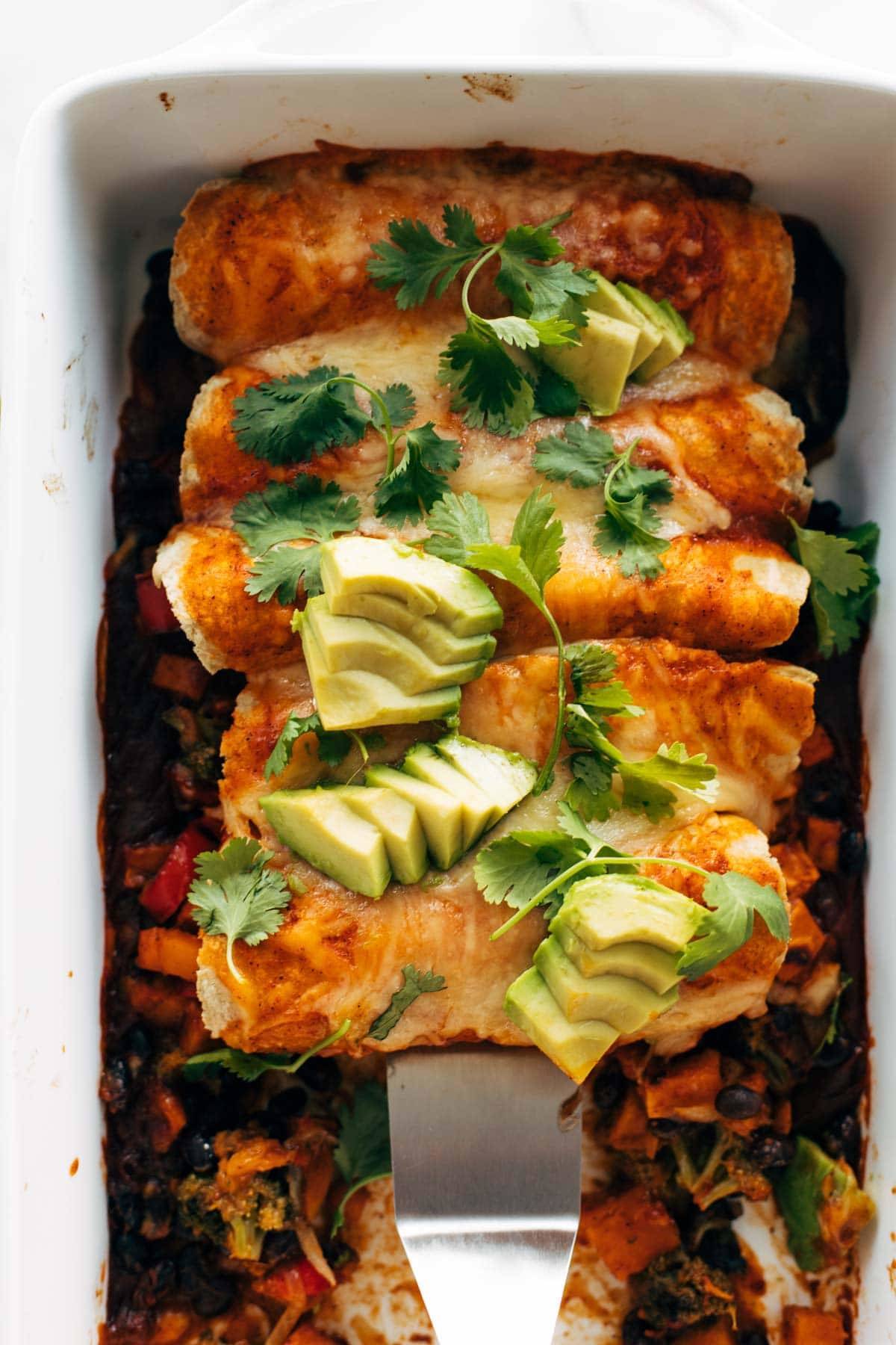 Sweet Potato black bean vegetarian enchiladas with avocados in a tray.