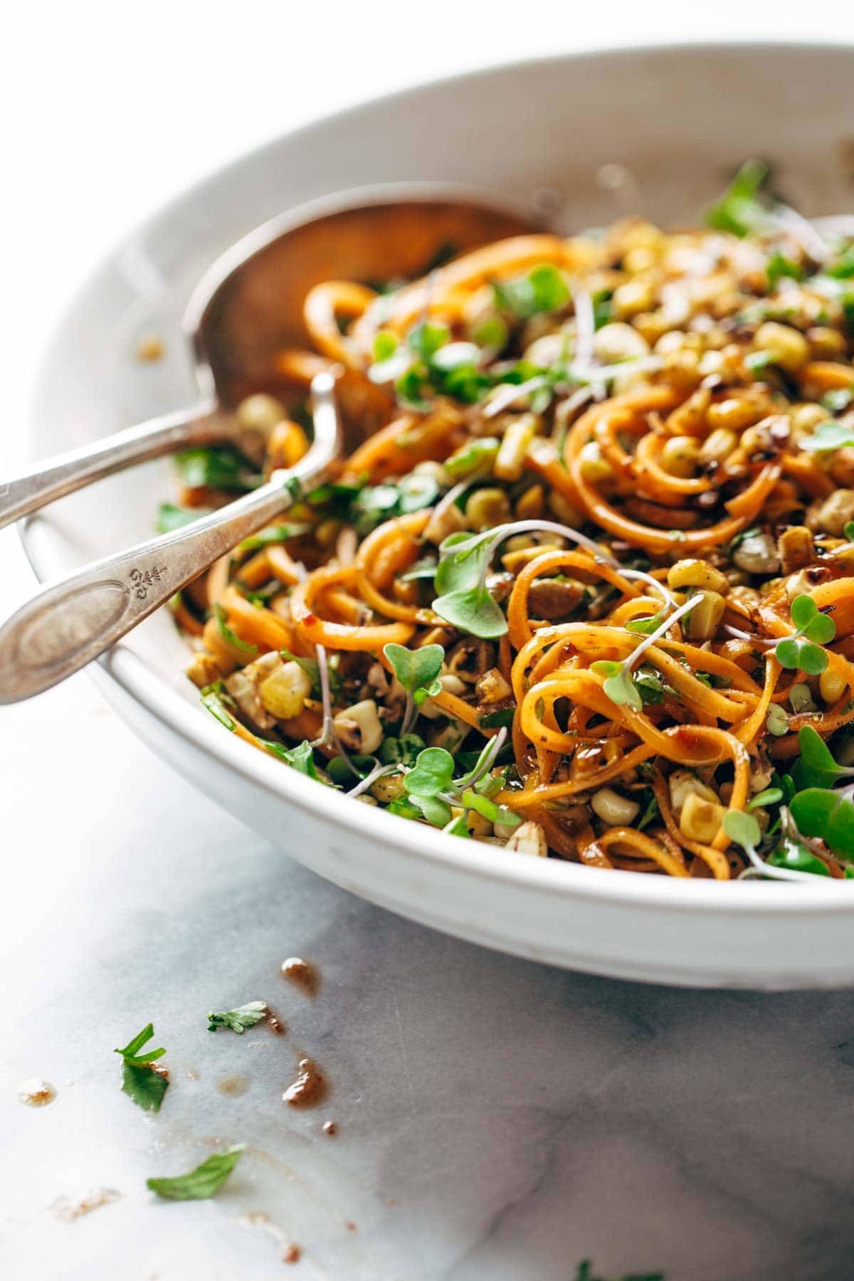 Noodle salad in a bowl with two spoons.