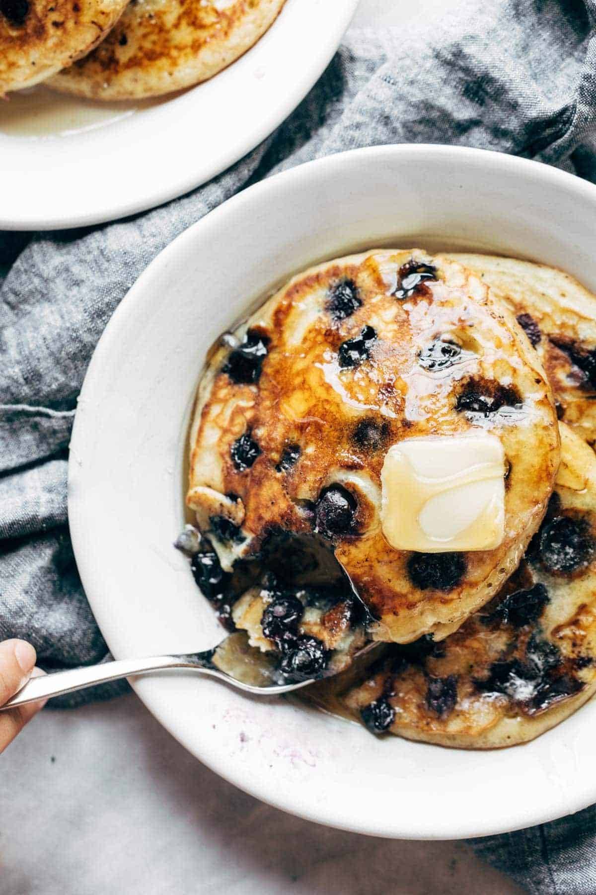 Blueberry pancakes on a plate with syrup and butter.