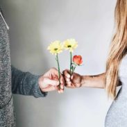 One man and a woman is holding flowers in their hands and holding hands together.