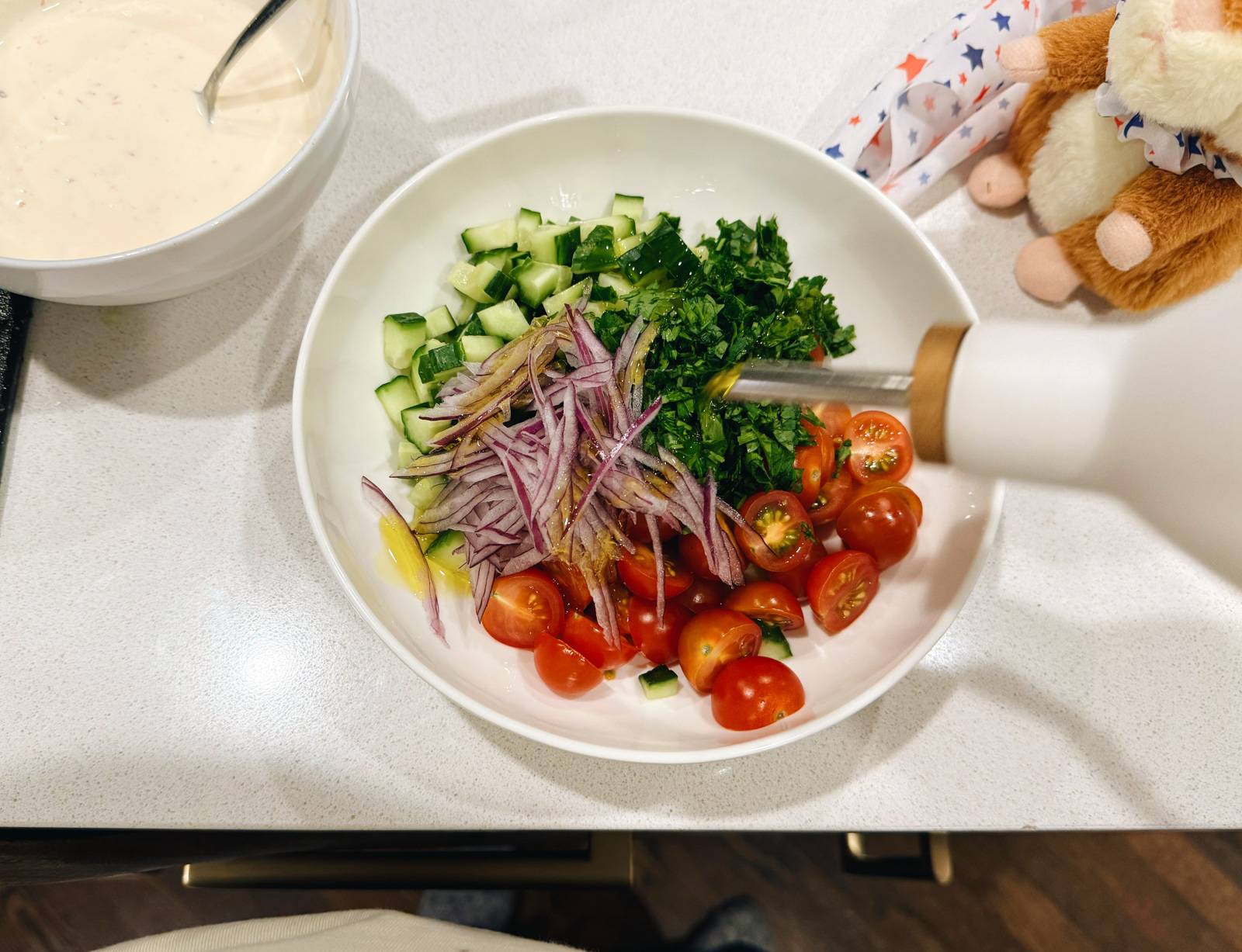 Drizzling olive oil over veggies in a bowl.