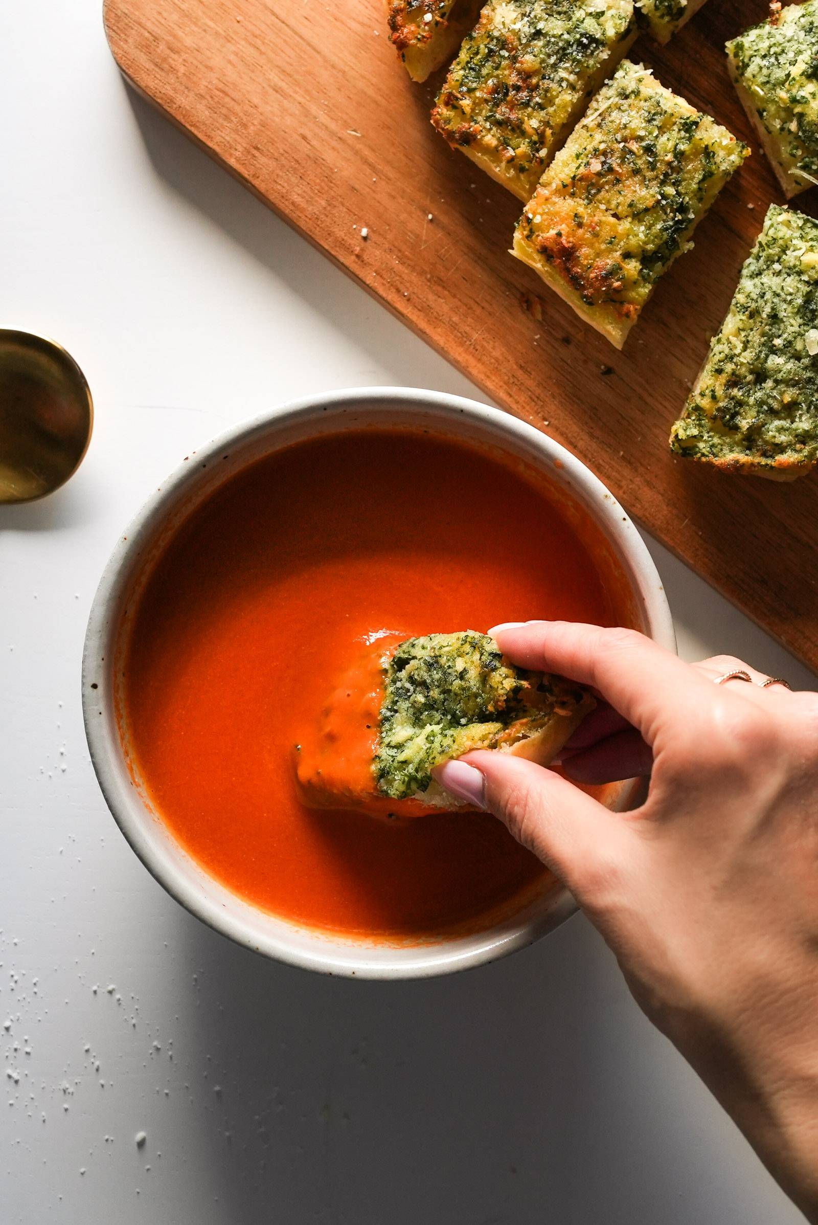 Dipping garlic bread into a bowl of tomato soup.