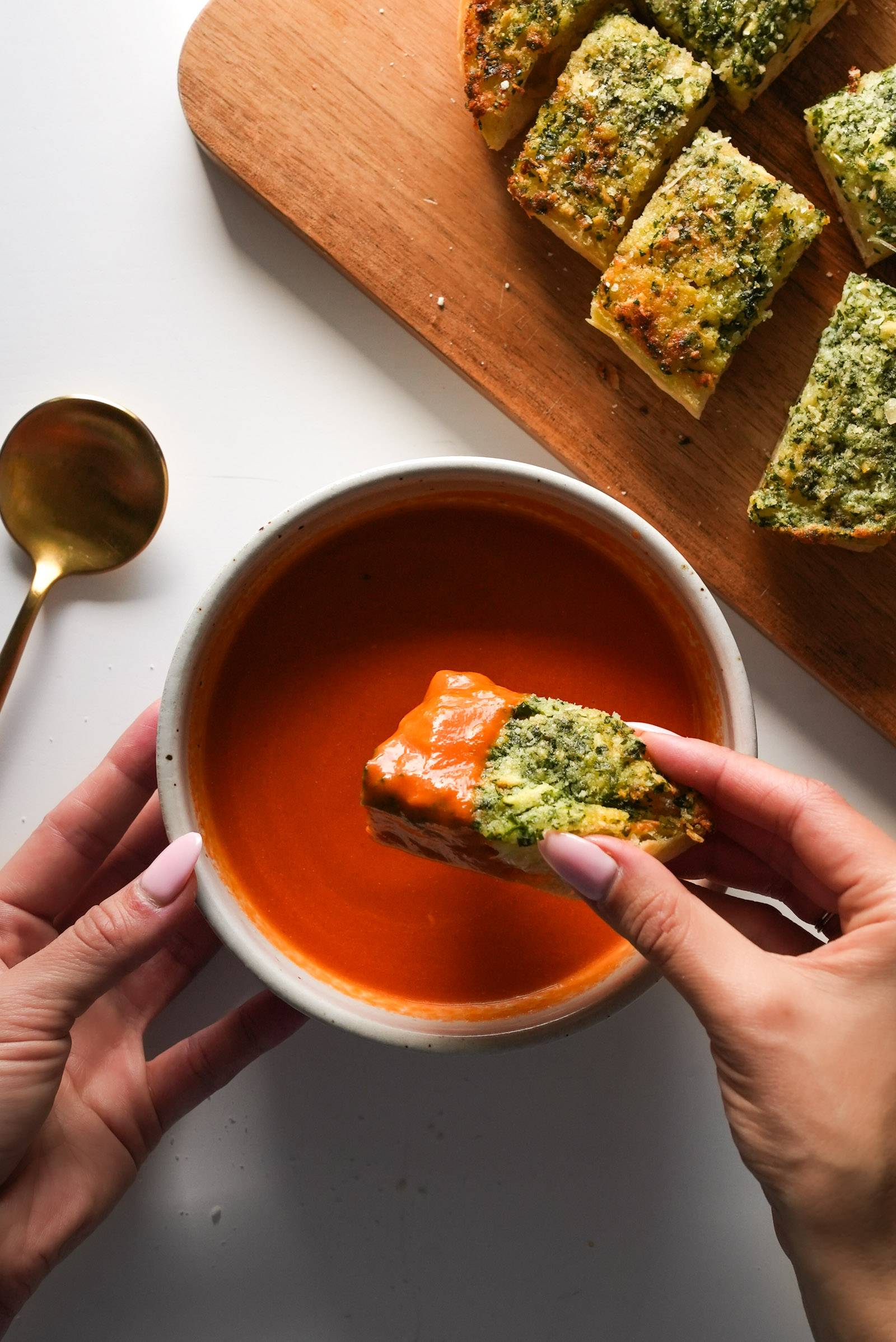 Dipping garlic bread into a bowl of tomato soup.