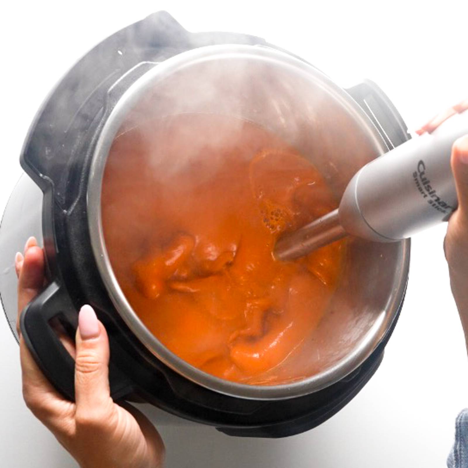 Blending tomato soup with an immersion blender.