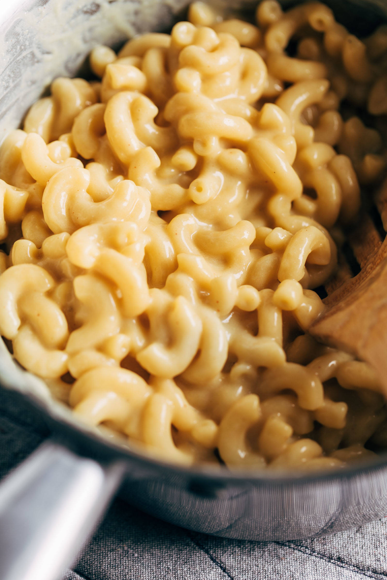 Vegan mac and cheese in a pot with a wooden spoon.