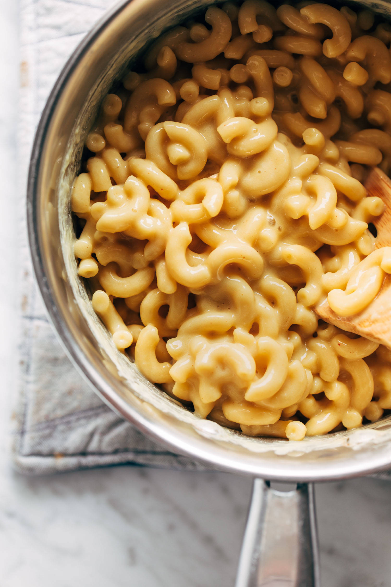 Vegan mac and cheese in a pot with a wooden spoon. 