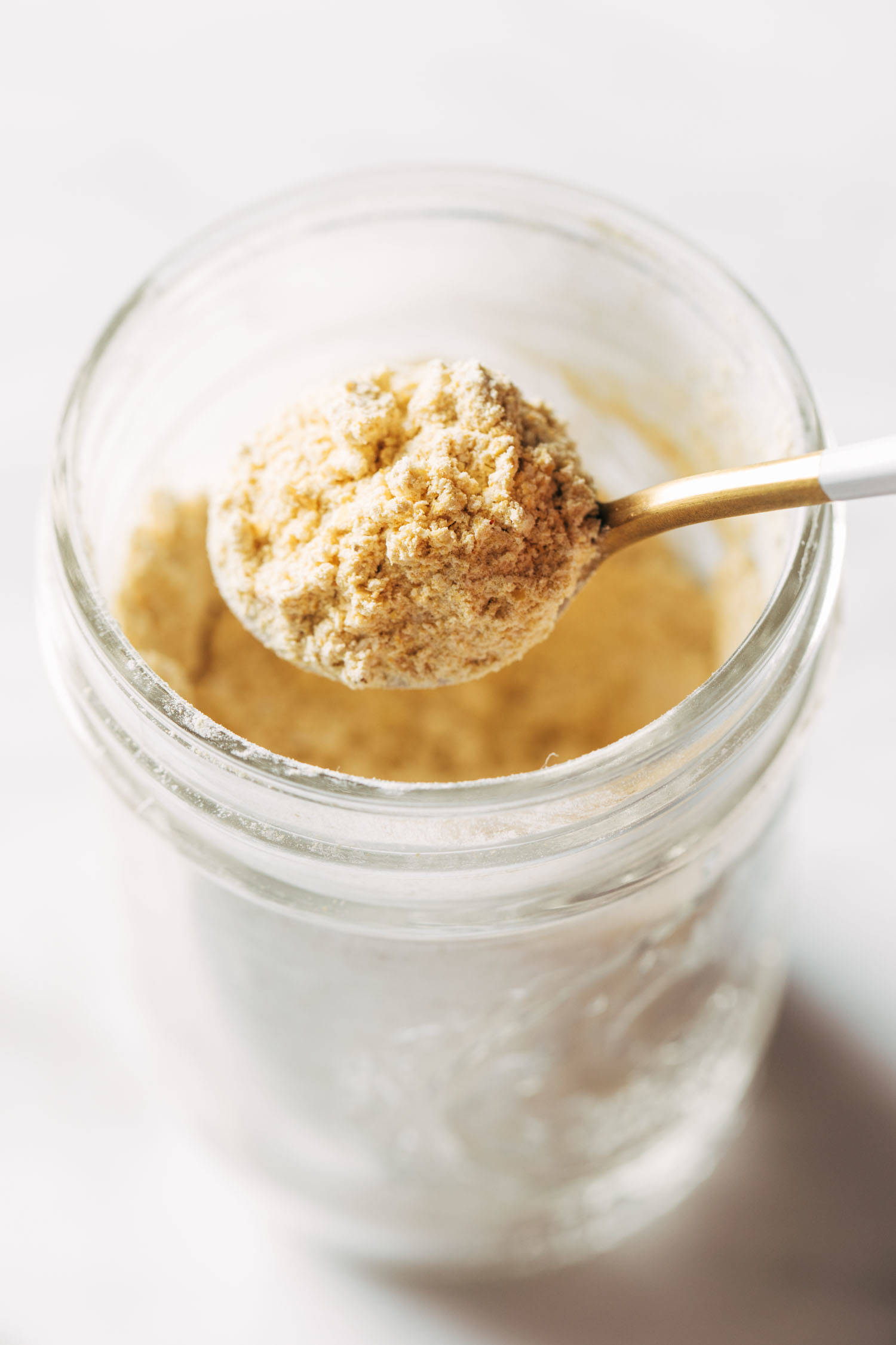 Vegan cheese powder being scooped with a spoon.