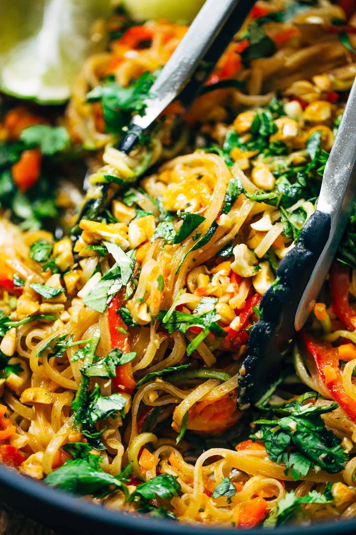 Vegetarian Pad Thai being scooped up with tongs