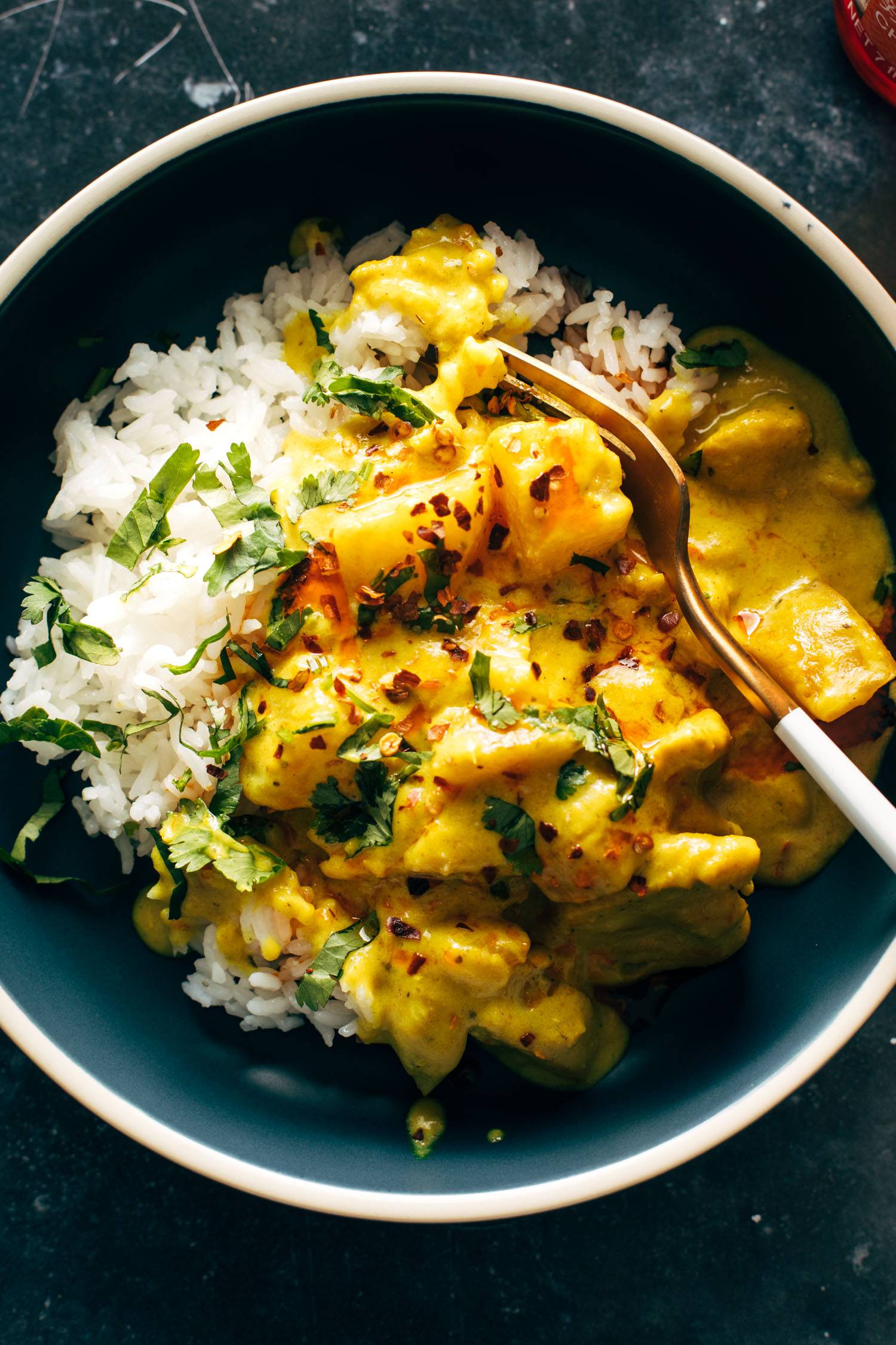 Yellow chicken curry in a bowl with a fork